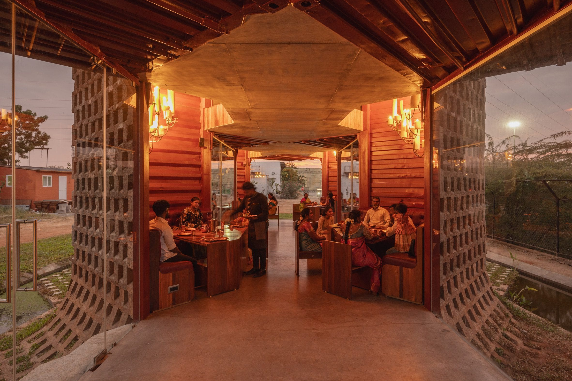 Interieur van het restaurant met dieprood geschilderde wanden van containerstaal en houten meubels.