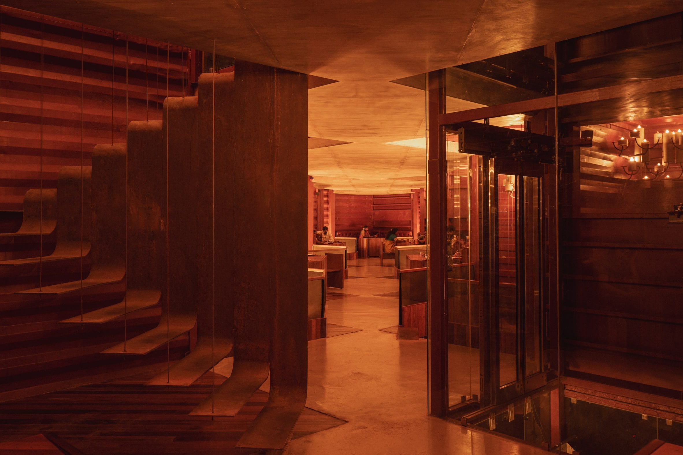 Interieur van het restaurant met dieprood geschilderde wanden van containerstaal en houten meubels.