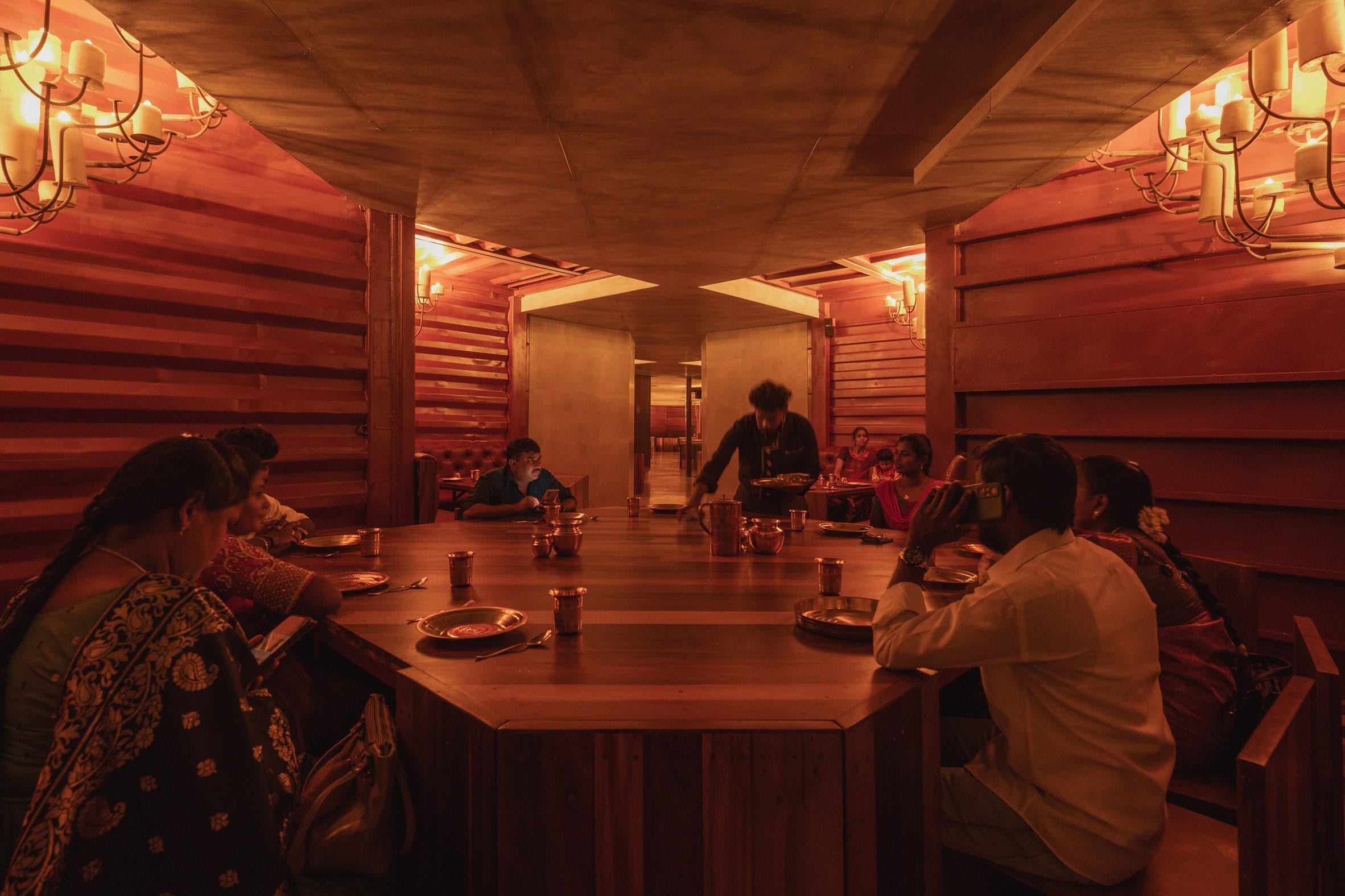 Interieur van het restaurant met dieprood geschilderde wanden van containerstaal en houten meubels.