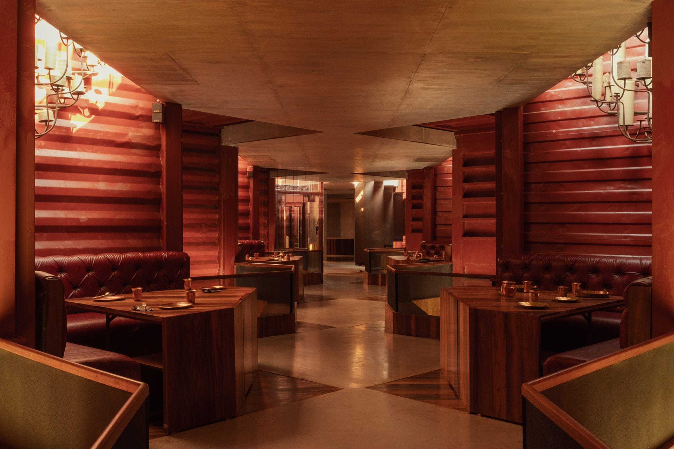 Interieur van het restaurant met dieprood geschilderde wanden van containerstaal en houten meubels.