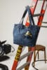 Blauwe denim shopper van Guess met een Minion-sleutelhanger, hangend aan een rode ladder in een fotostudio