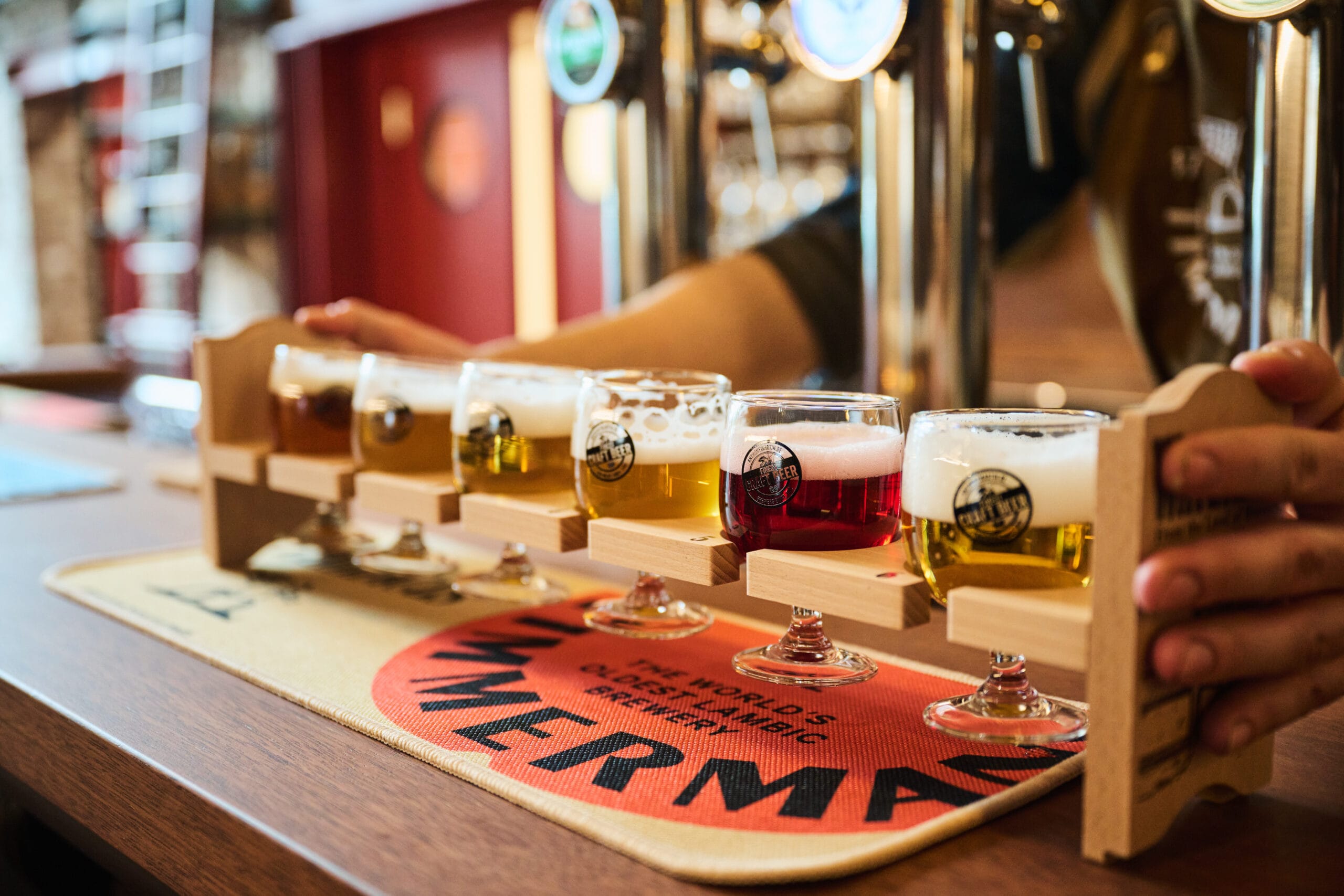 Een houten houder met zes verschillende proefglazen speciaalbier op een bar bij een tapinstallatie