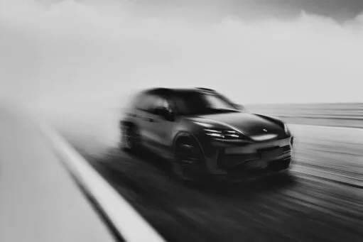 Een wazige zwart-witfoto van een sportieve SUV die met hoge snelheid over een weg rijdt