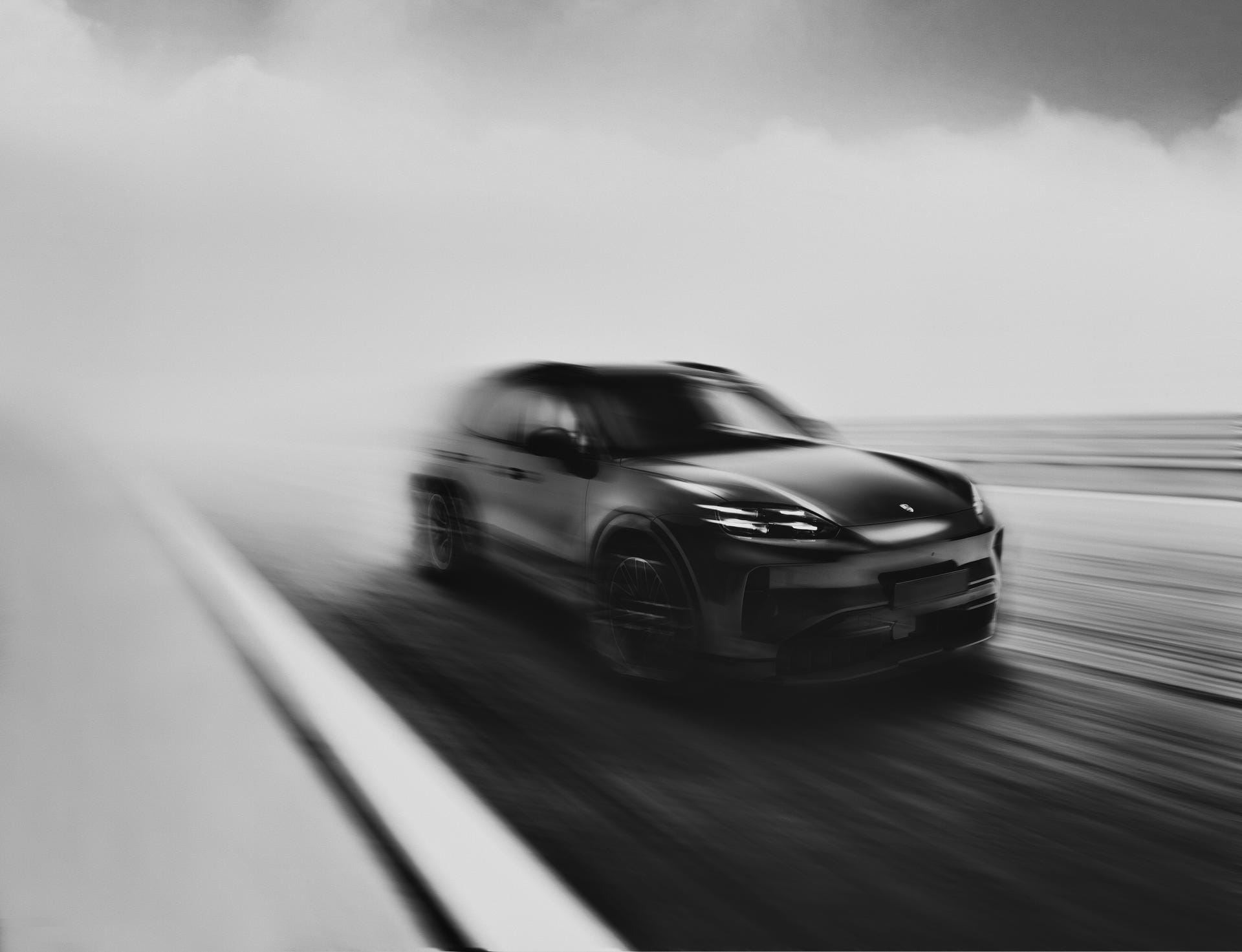Een wazige zwart-witfoto van een sportieve SUV die met hoge snelheid over een weg rijdt