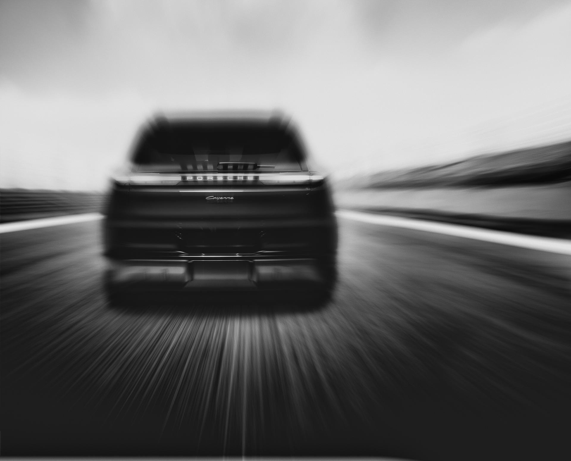Zwart-witfoto van de achterzijde van een Porsche Cayenne met abstracte bewegingsonscherpte die snelheid suggereert