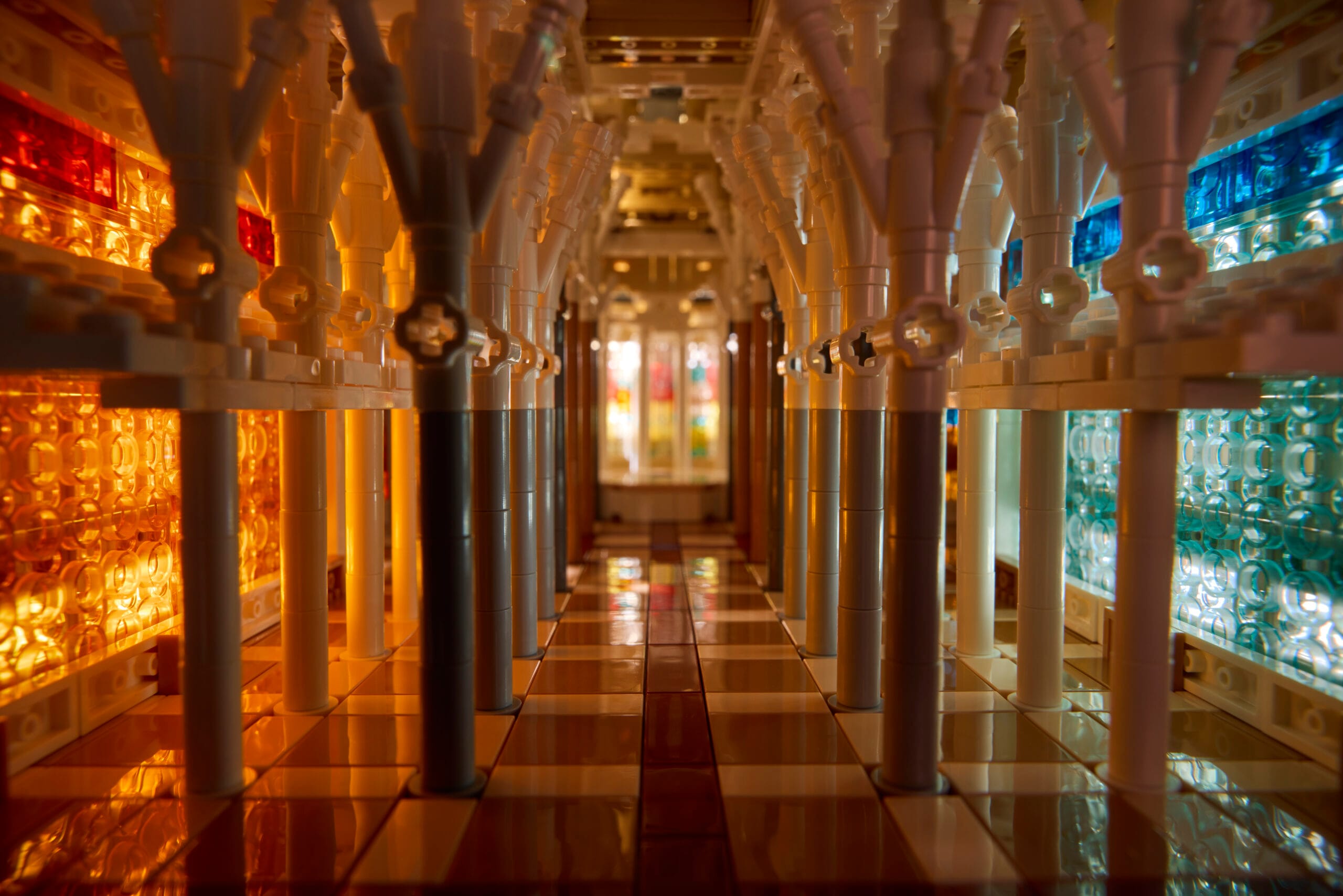 Interieur van een miniatuurkathedraal gebouwd van bouwsteentjes met witte zuilen en kleurrijke glas-in-loodramen