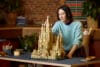 Een vrouw plaatst het laatste onderdeel op een gedetailleerd LEGO model van de Sagrada Família