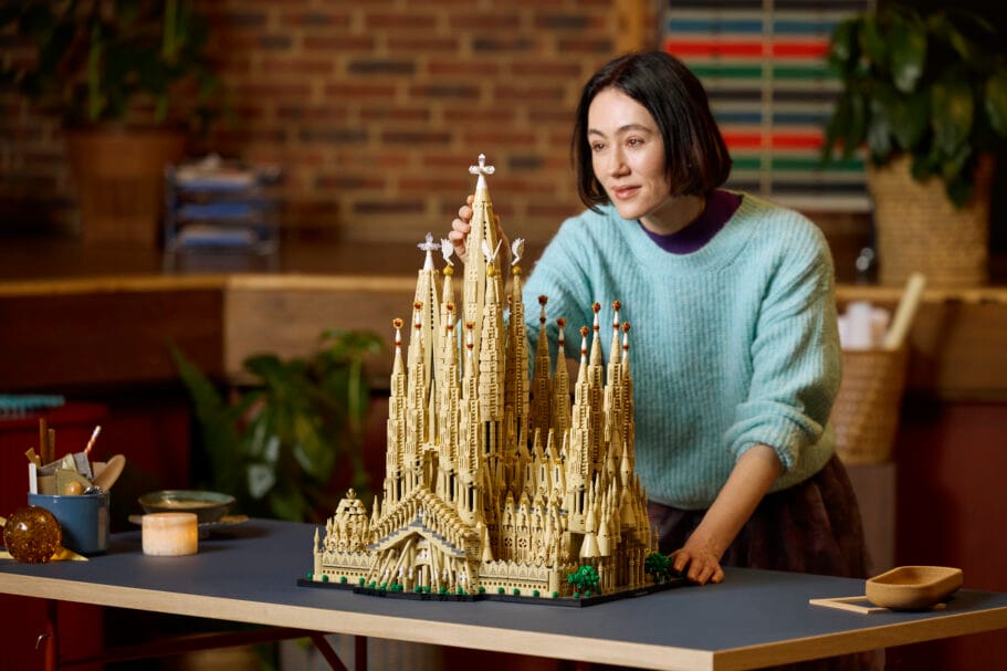 Een vrouw plaatst het laatste onderdeel op een gedetailleerd LEGO model van de Sagrada Família