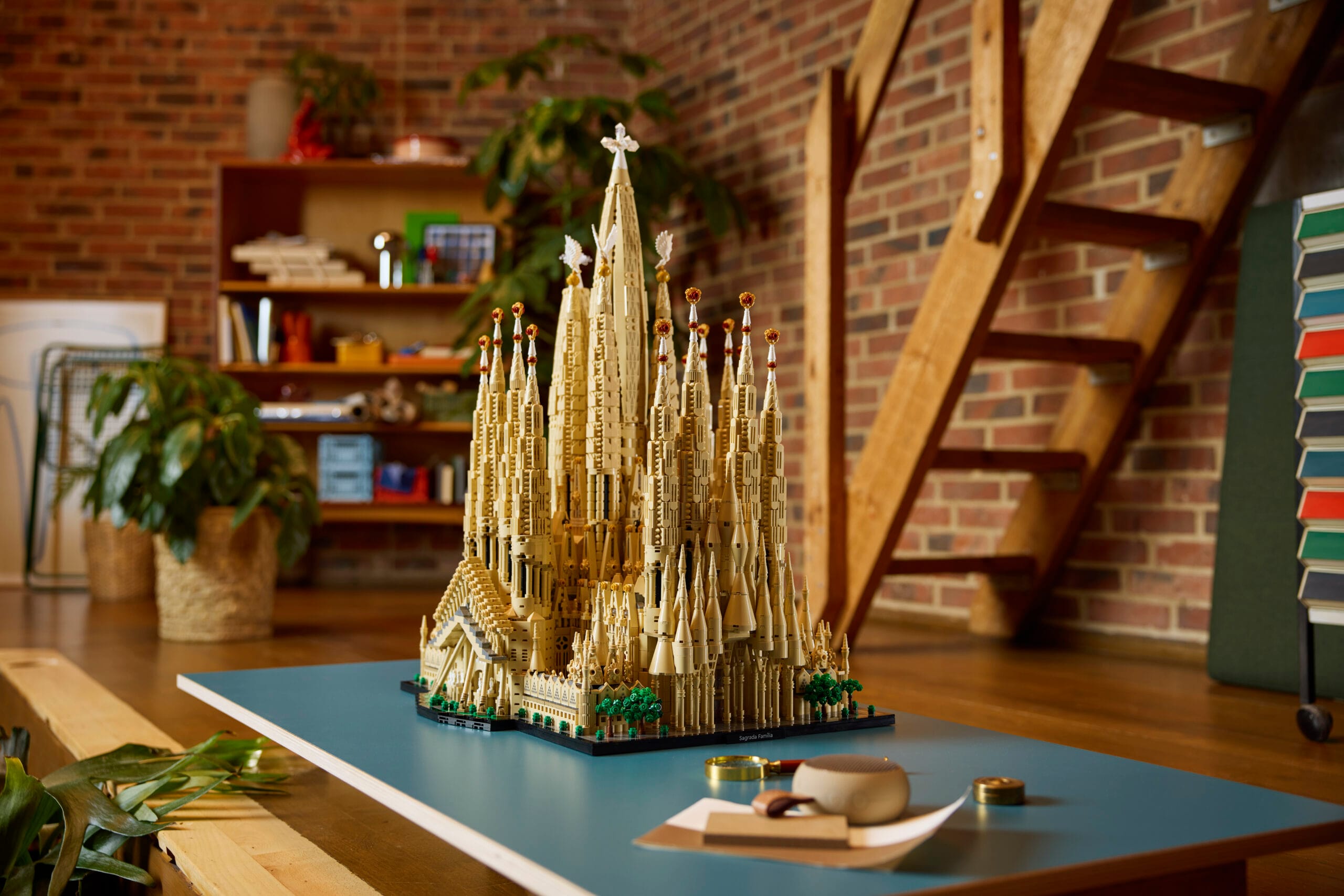 Een gedetailleerd LEGO-model van de Sagrada Família op een blauwe tafel in een woonkamer