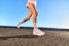 Hardloopschoenen ASICS GEL-KAYANO 33 van een renner die over een geasfalteerd pad loopt tegen een strakblauwe lucht