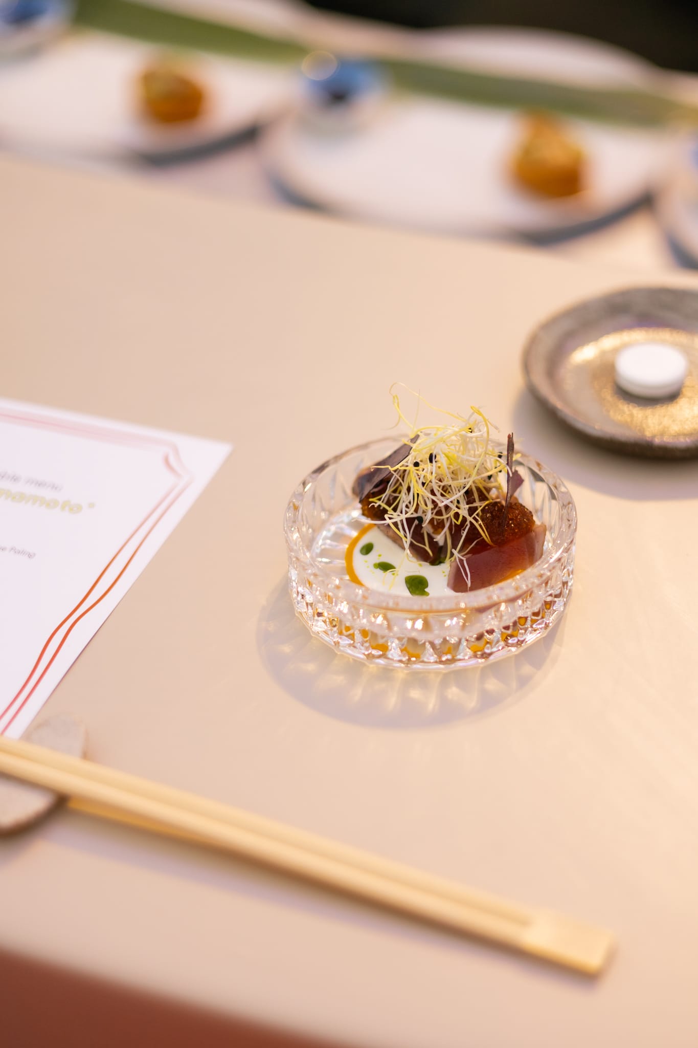 Een verfijnd gerechtje van rauwe vis in een kristallen schaaltje, gegarneerd met kiemgroenten en geserveerd met eetstokjes tijdens het food festival Bite of Amsterdam in het Amstelpark