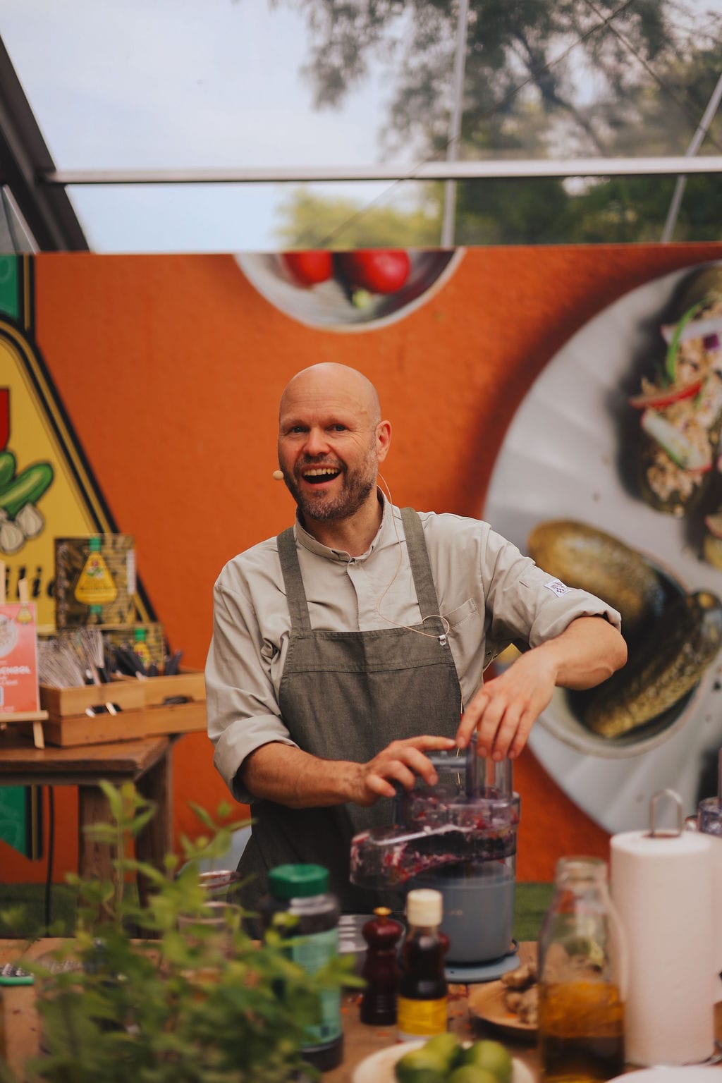 Een lachende chef-kok met een schort aan bedient een keukenmachine tijdens een kookdemonstratie op het foodfestival Bite of Amsterdam