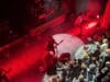 Metalband Blood Incantation treedt op een donker podium op met felrode belichting, terwijl fans vooraan bij het podium toekijken