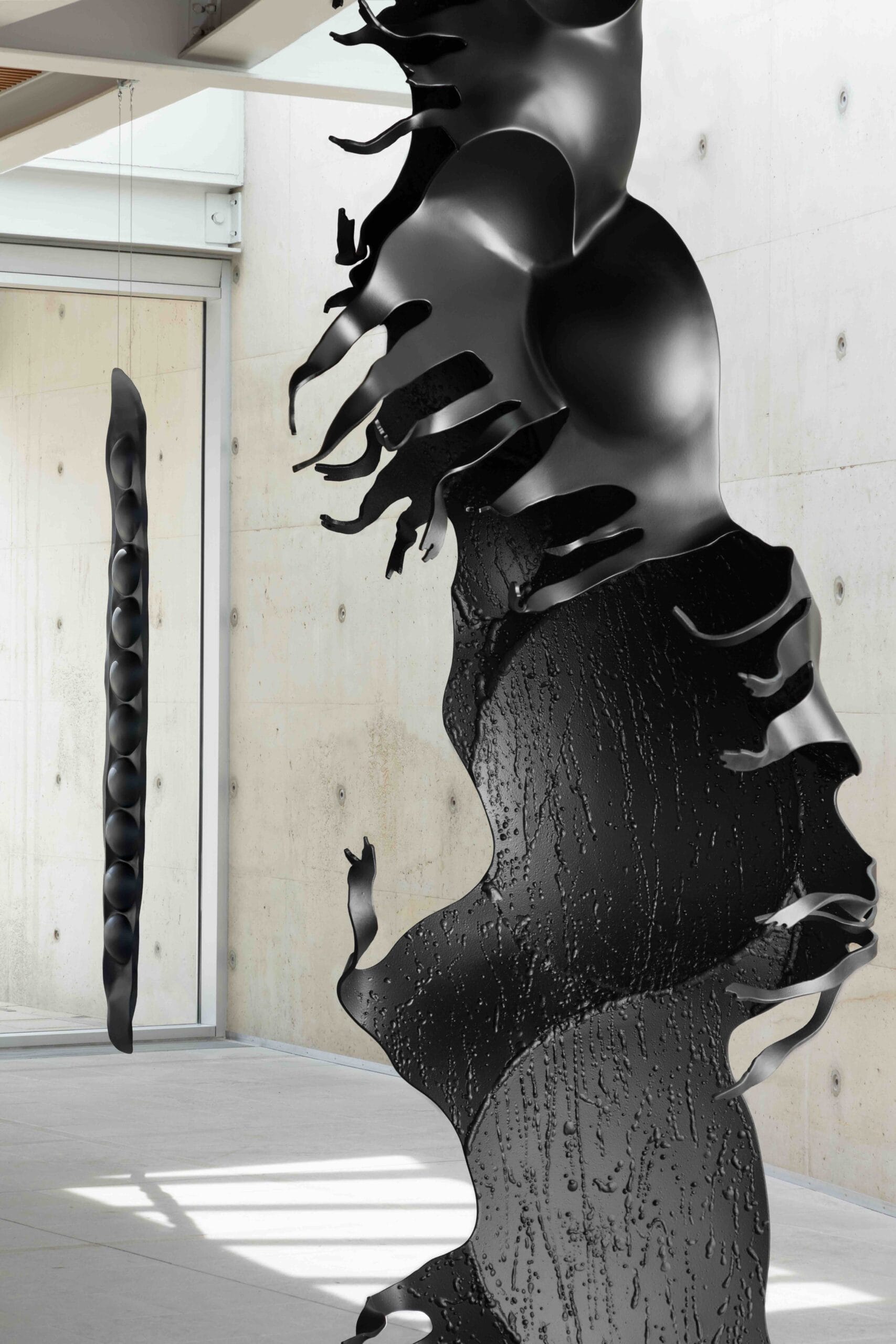 Een abstract zwart sculptuur met vloeiende, grillige vormen en een getextureerd oppervlak van Chafes x Giacometti in een moderne expositieruimte van Museum Beelden aan Zee in Den Haag