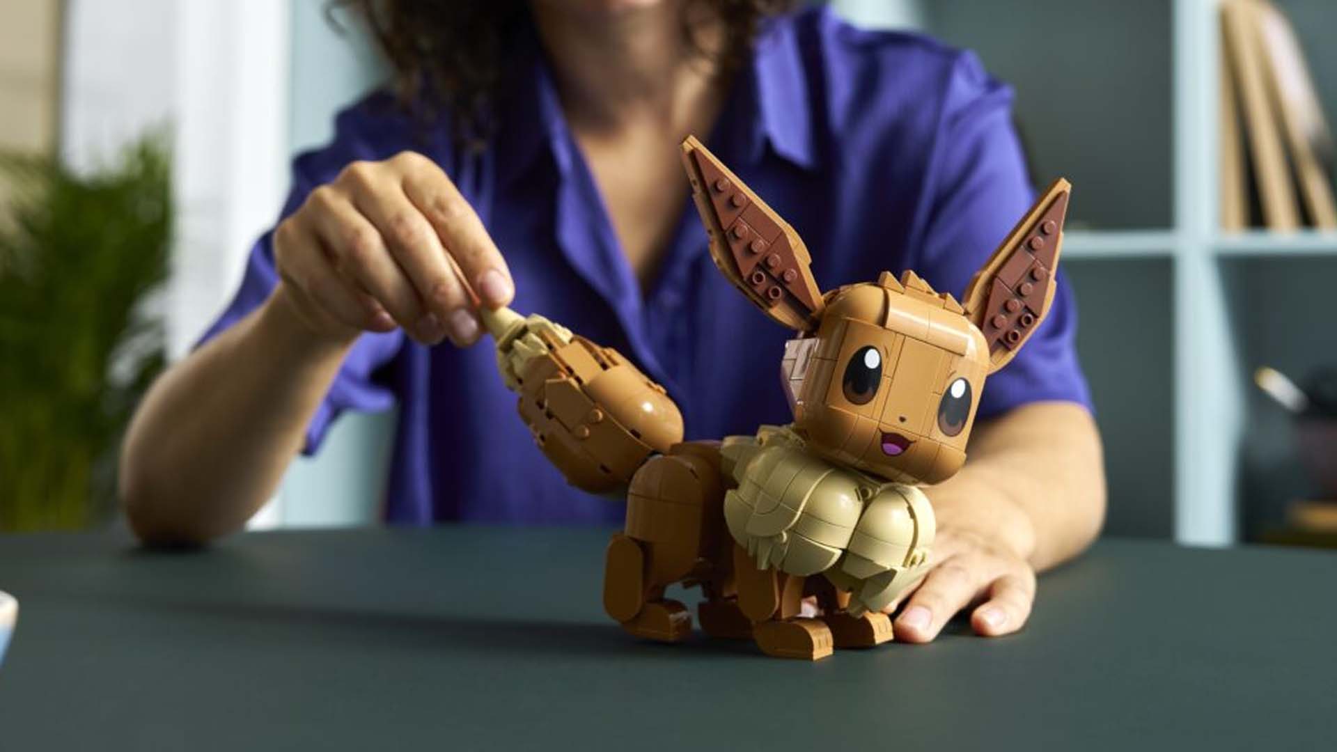 Een persoon bouwt een gedetailleerd model van de Pokémon Eevee met bouwsteentjes