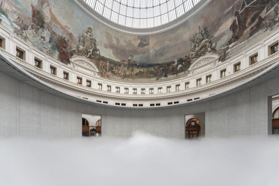 Een dikke laag witte mist vult de ronde centrale hal van de Bourse de Commerce onder een koepel met historische fresco's