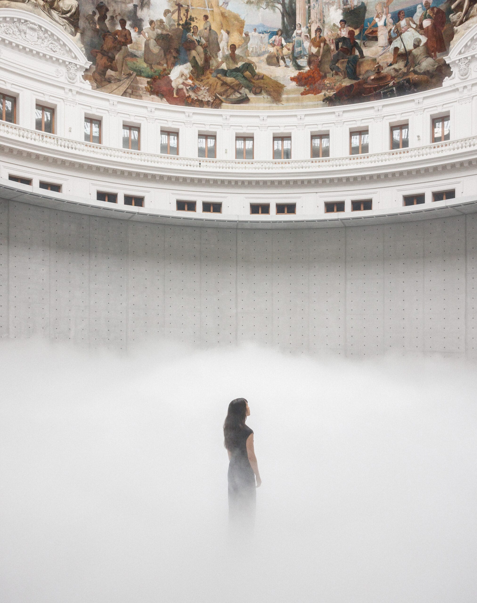 Een vrouw staat in een dichte mist onder de koepel van de Bourse de Commerce in Parijs