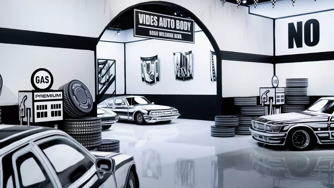 Een zwart-wit kunstinstallatie van Joshua Vides met auto's en garage-elementen in een cartoonachtige schetsstijl