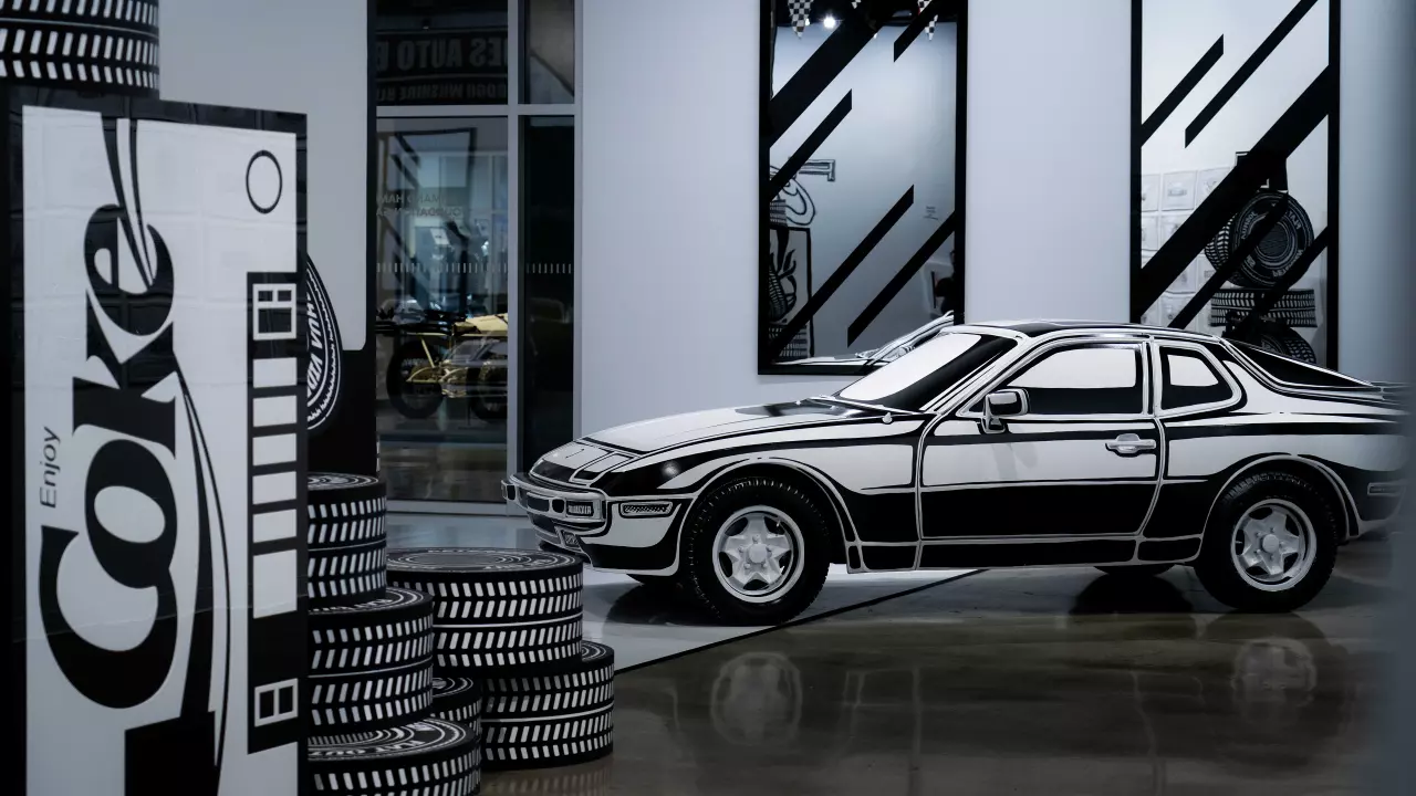 Een sportwagen beschilderd in een zwart-witte cartoonstijl in een modern museum