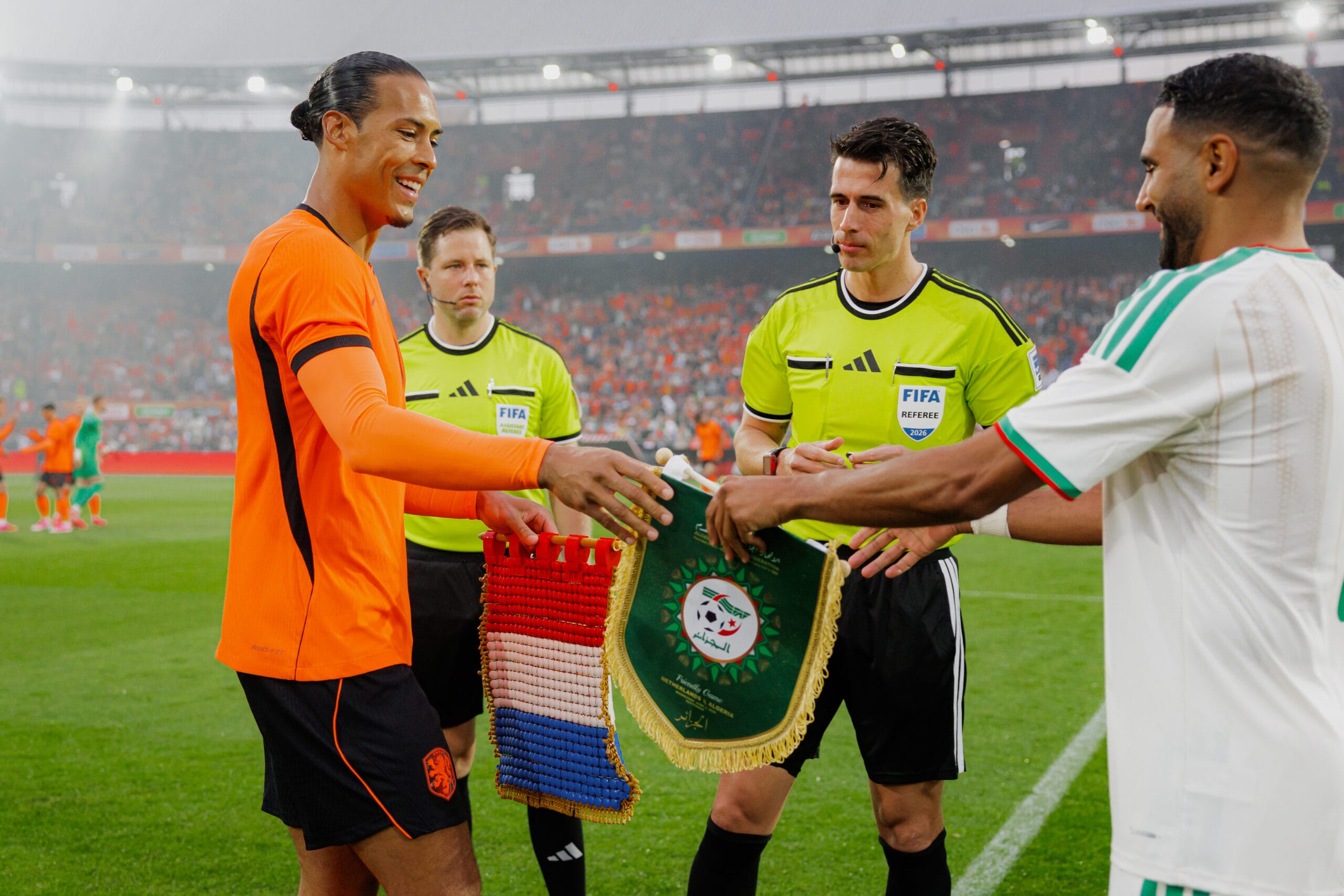 Virgil van Dijk en de Algerijnse aanvoerder wisselen vaantjes uit voor de wedstrijd onder toezicht van de scheidsrechters