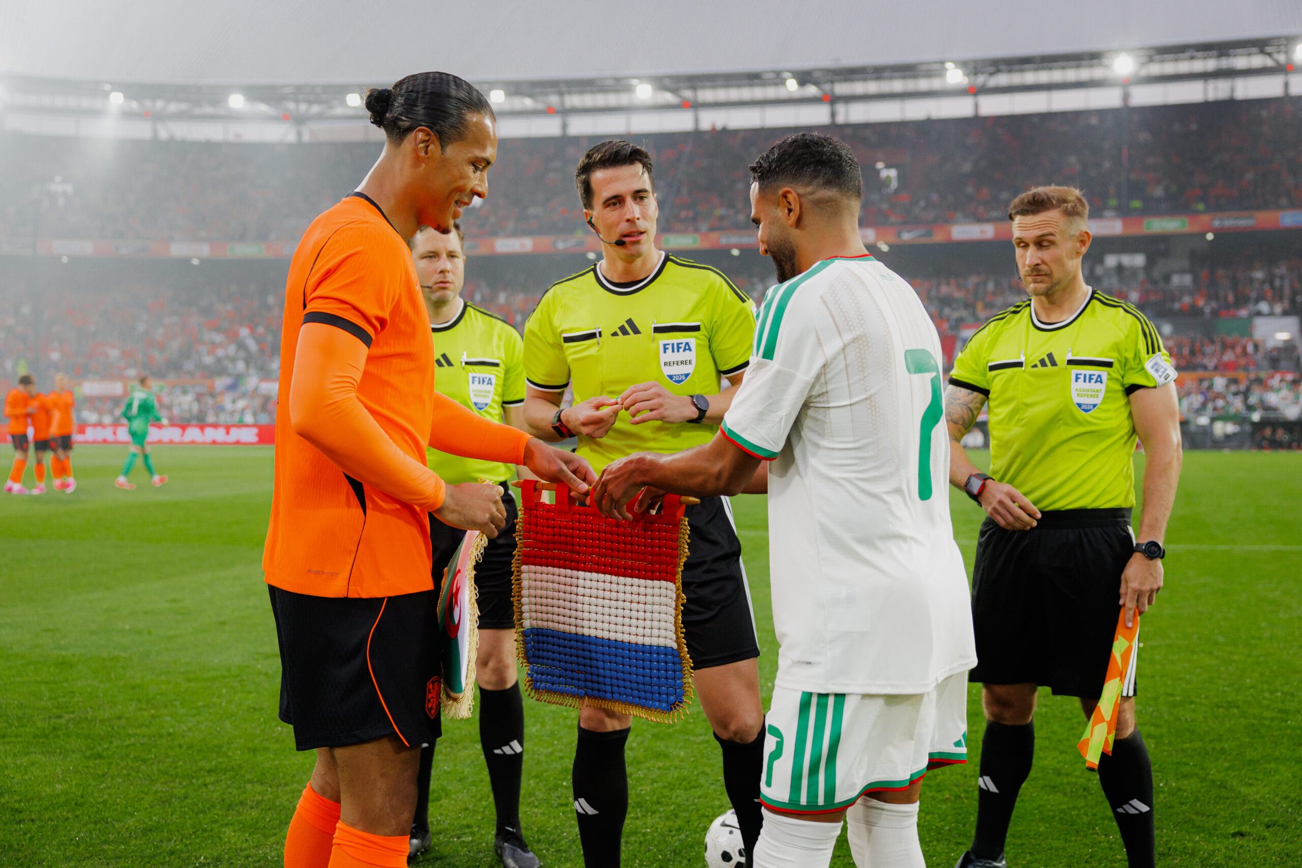Virgil van Dijk en de aanvoerder van Algerije wisselen vaantjes uit voor de wedstrijd onder toezicht van de scheidsrechters