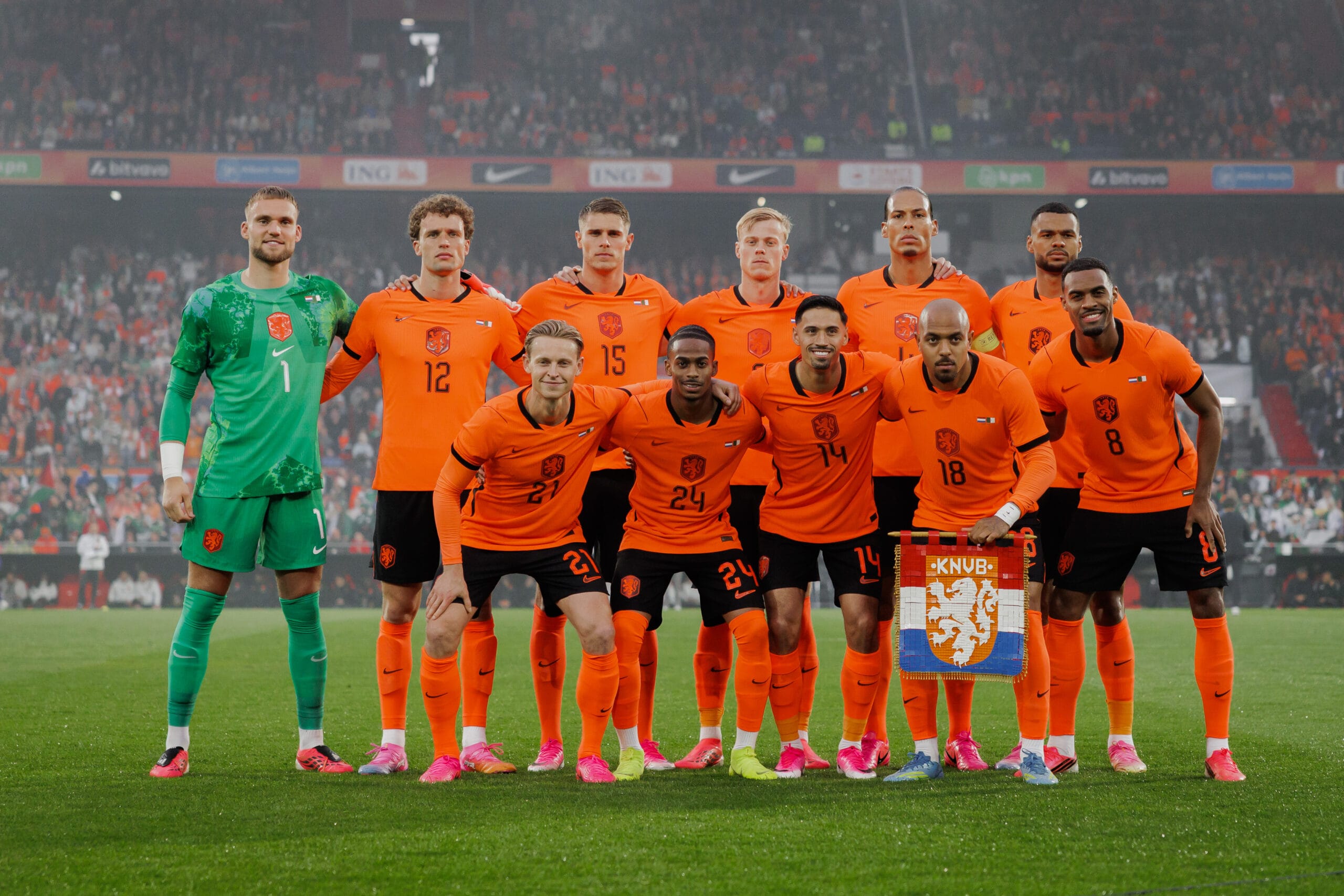 Het Nederlands elftal poseert voor de aftrap in een vol stadion. De spelers dragen het oranje thuistenue