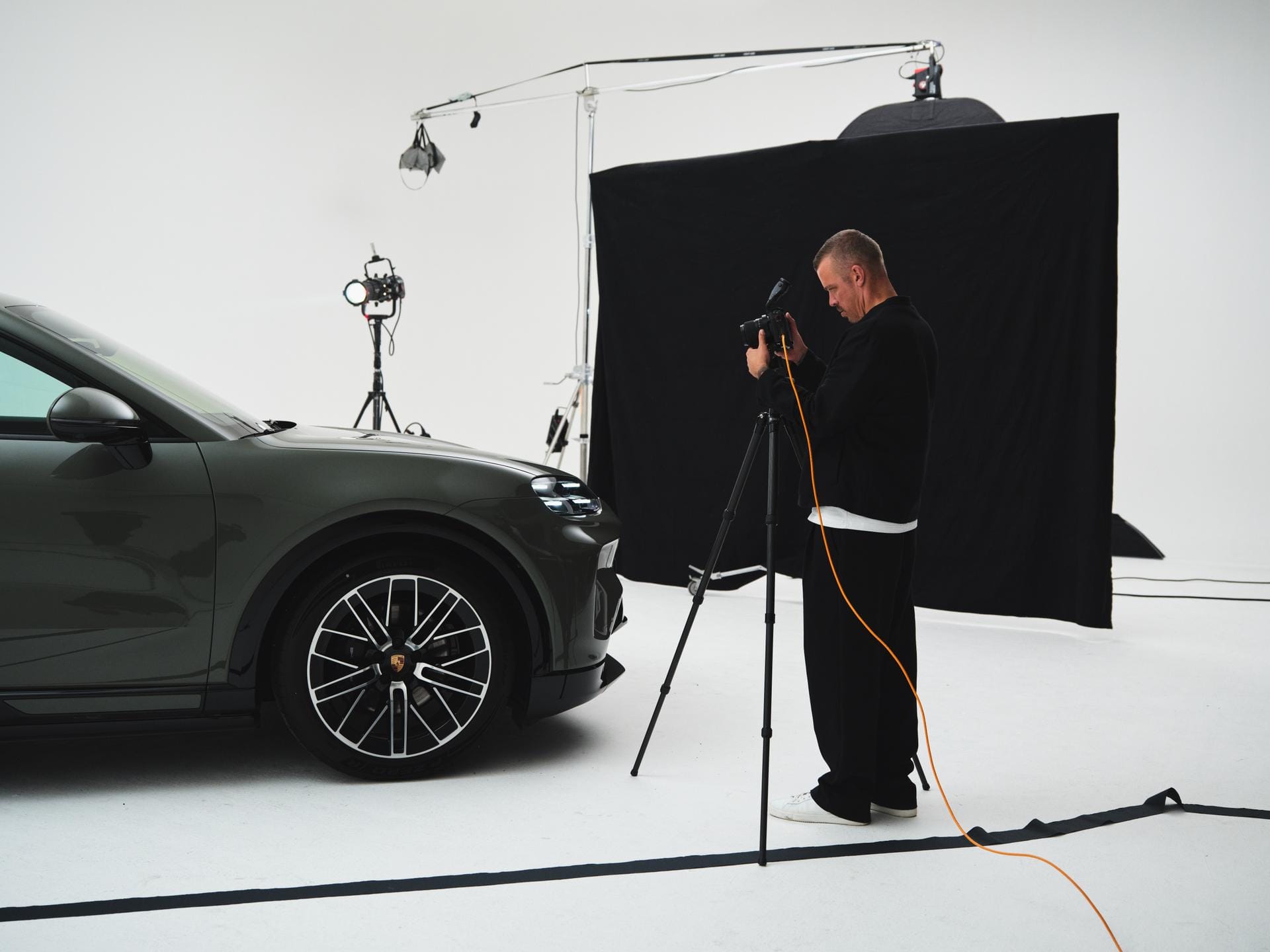 Een fotograaf maakt in een studio opnames van de voorzijde van een donkergroene Porsche