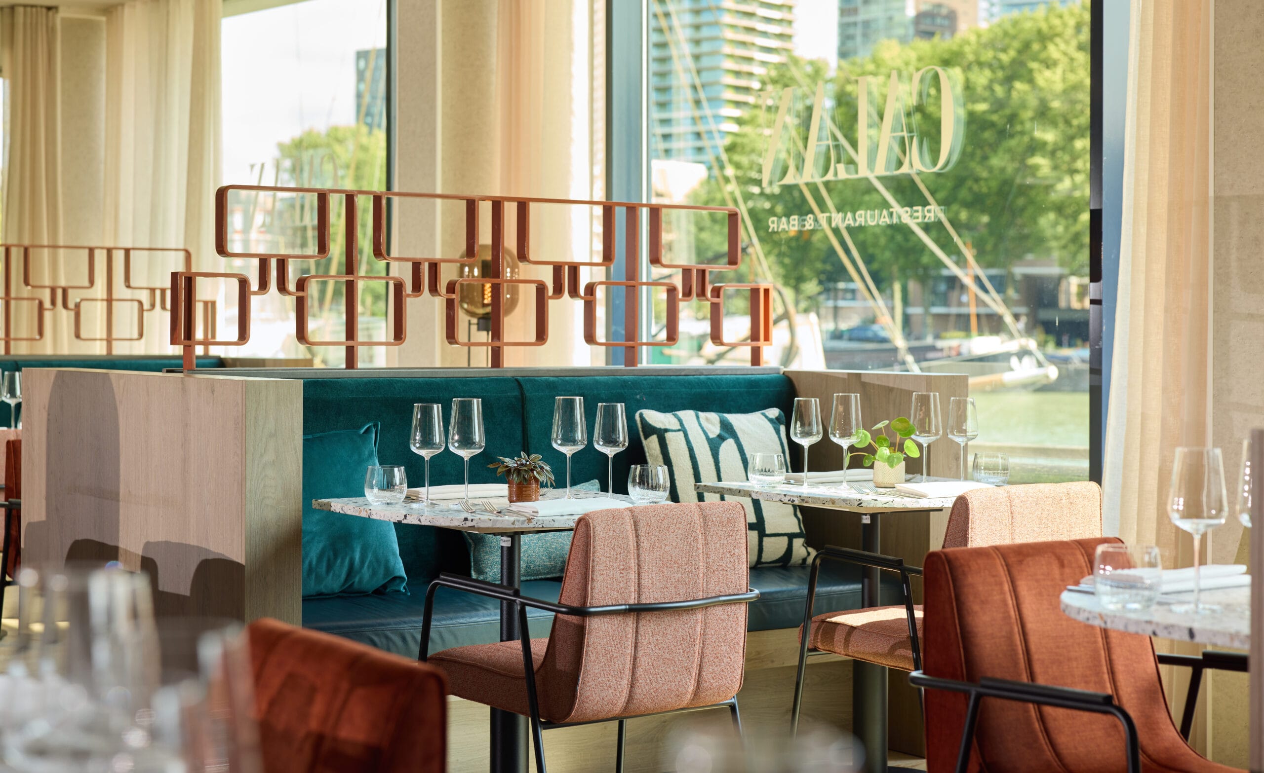 Modern interieur van Restaurant & Bar GAIA met gedekte marmeren tafels, fluwelen banken en uitzicht op de haven