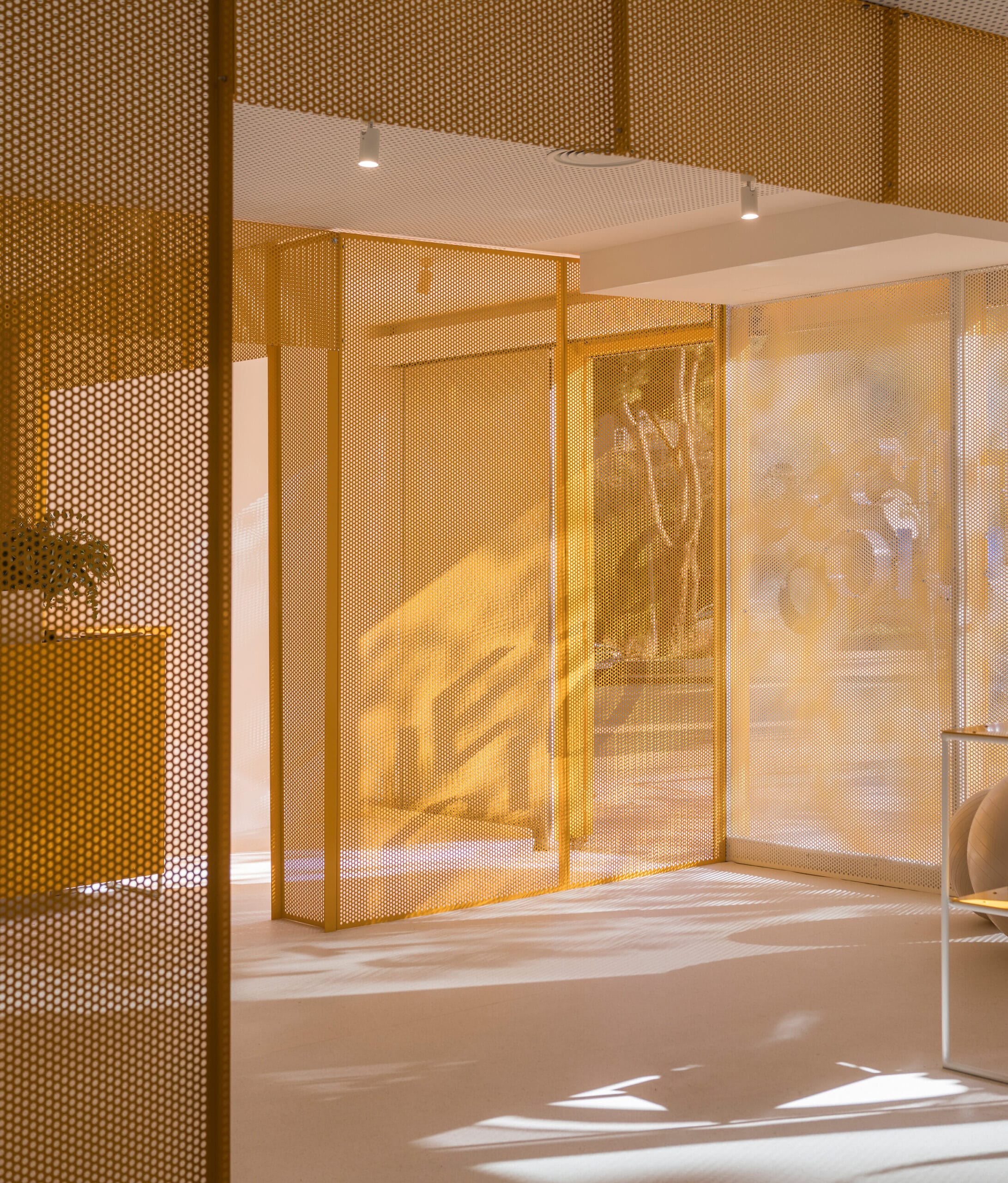 Modern interieur met gele geperforeerde metalen scheidingswanden en invallend zonlicht