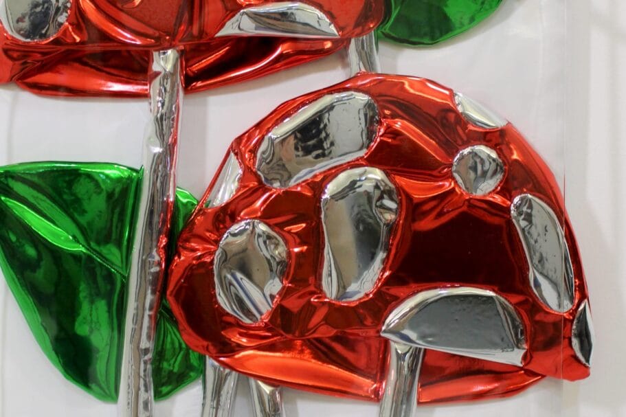 Glanzende sculptuur van rood-zilveren paddenstoelen met groene bladeren gemaakt van reflecterend folie-achtig materiaal