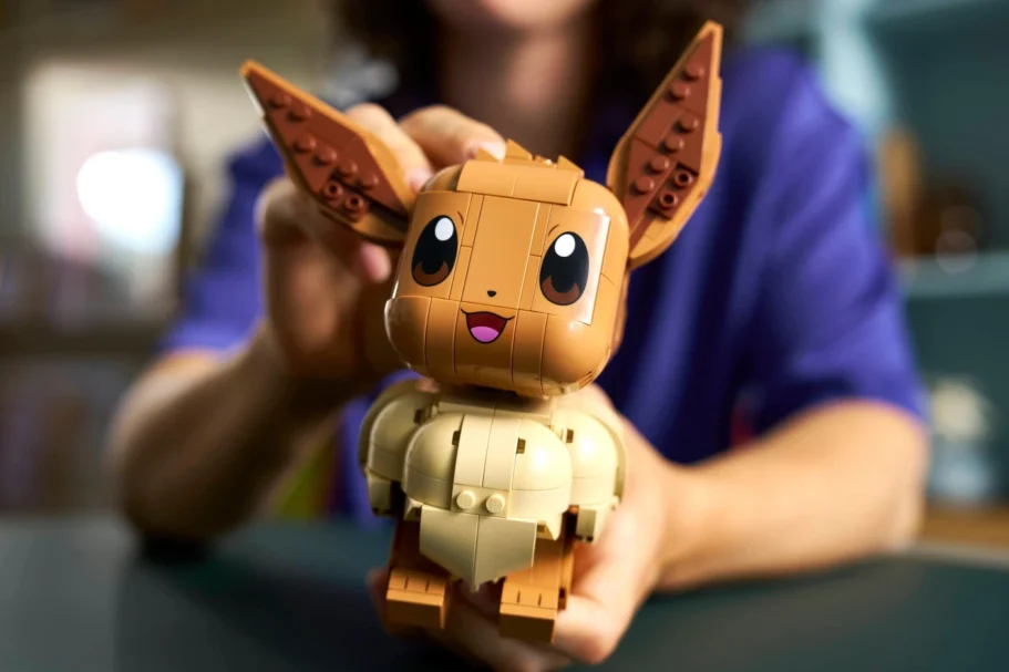Een persoon houdt een uit bouwstenen opgebouwde Pokémon Eevee vast