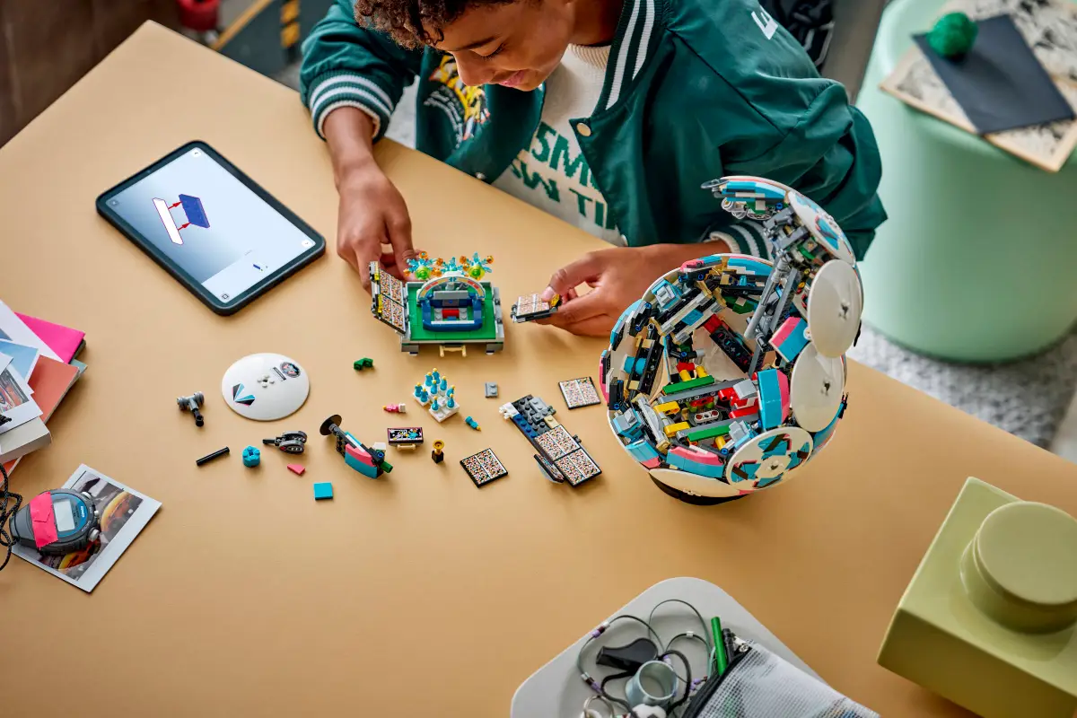 Een kind bouwt een kleurrijk LEGO-model aan een tafel met behulp van digitale instructies op een tablet