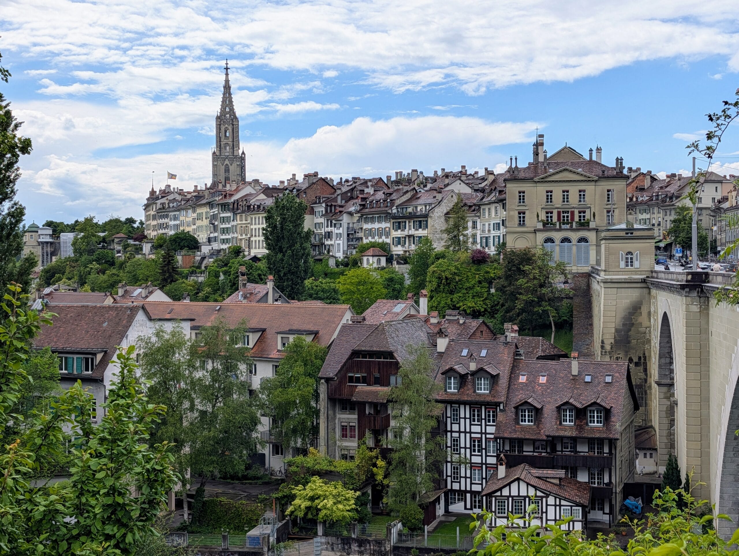 Gezicht op de oude binnenstad van Bern met de Berner Münster-toren boven historische huizen en de Nydeggbrücke