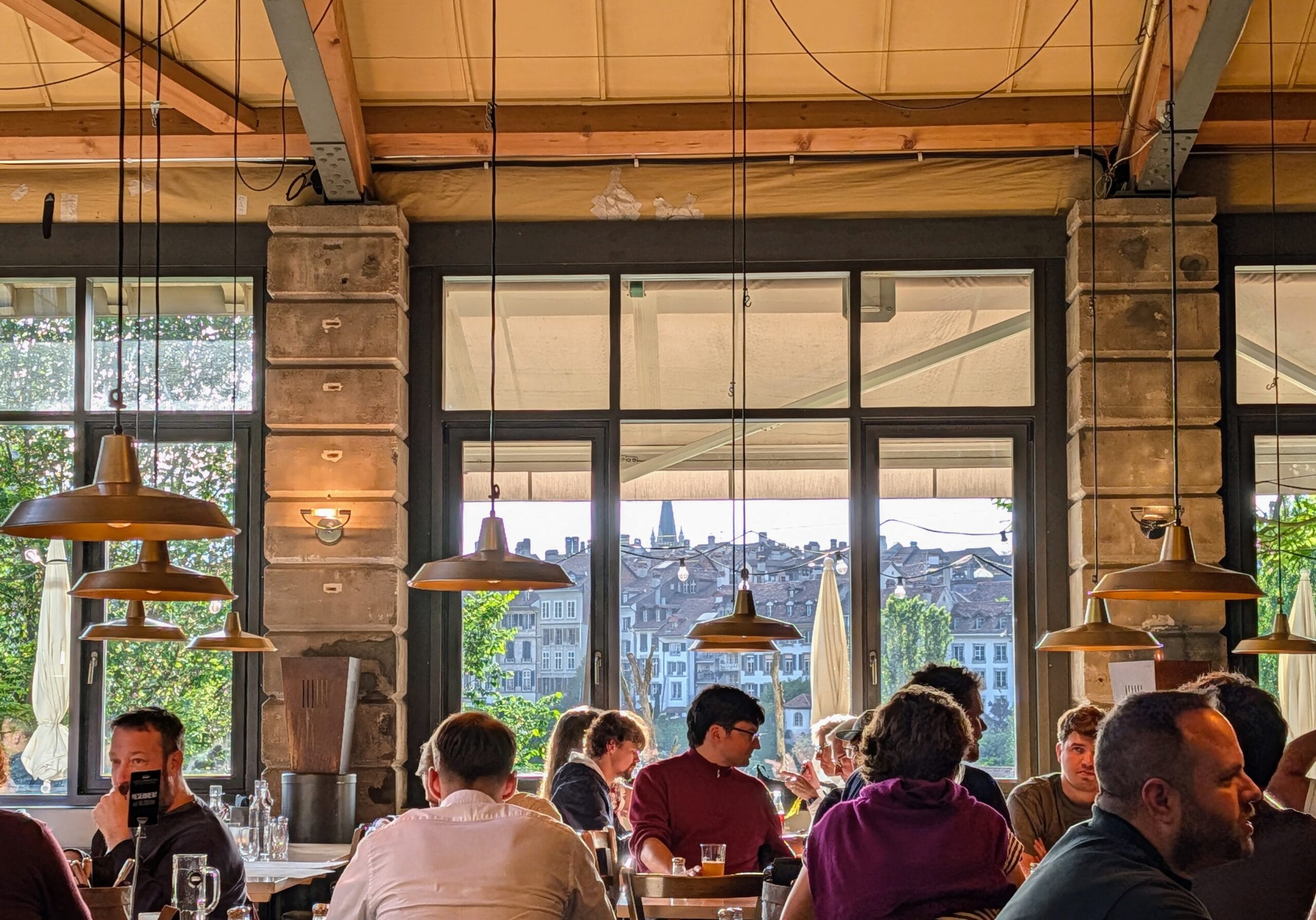 Mensen die dineren in een sfeervol restaurant met uitzicht op historische gebouwen in Bern