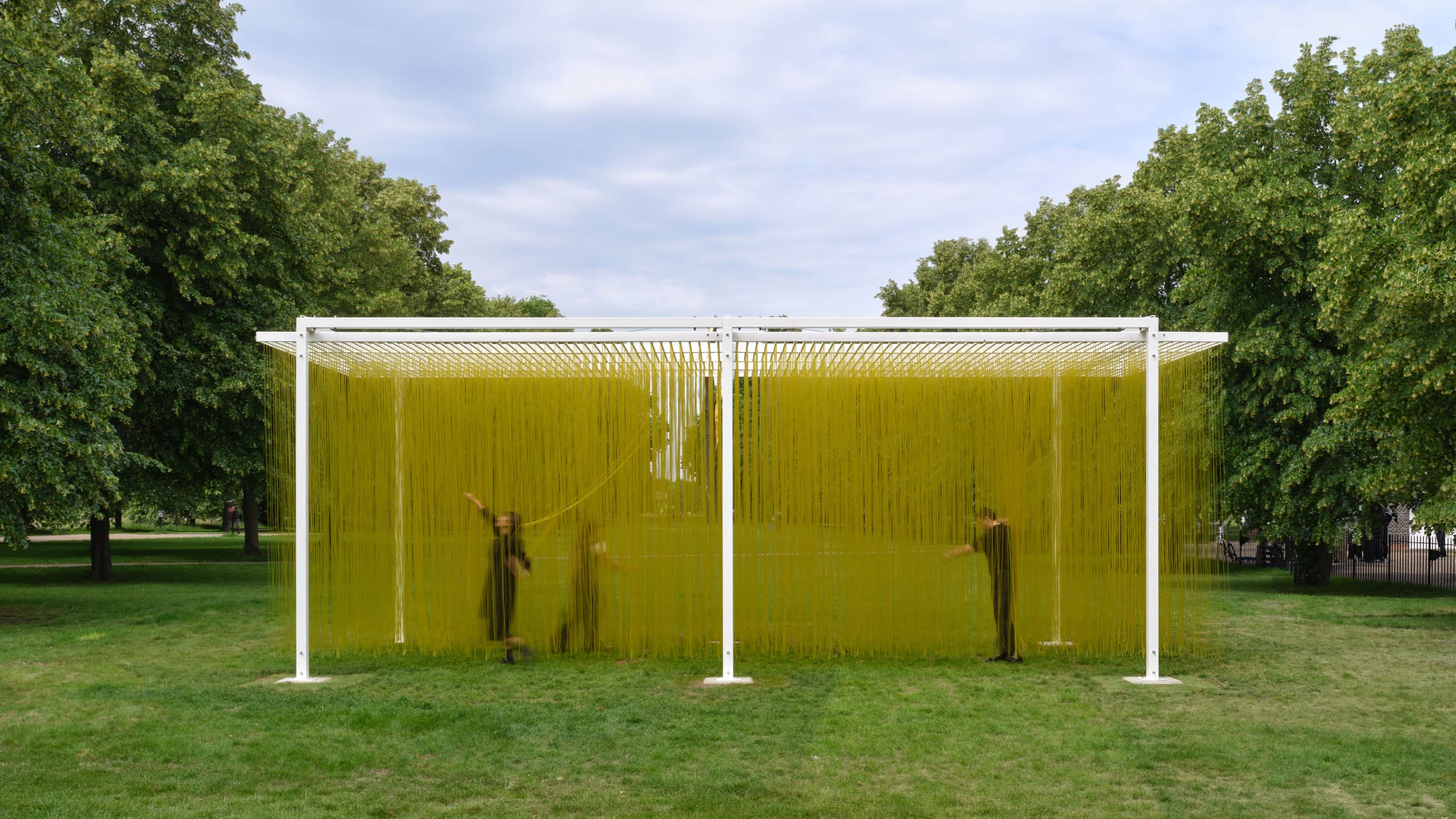 Mensen lopen door een kunstinstallatie van duizenden hangende gele draden in een park