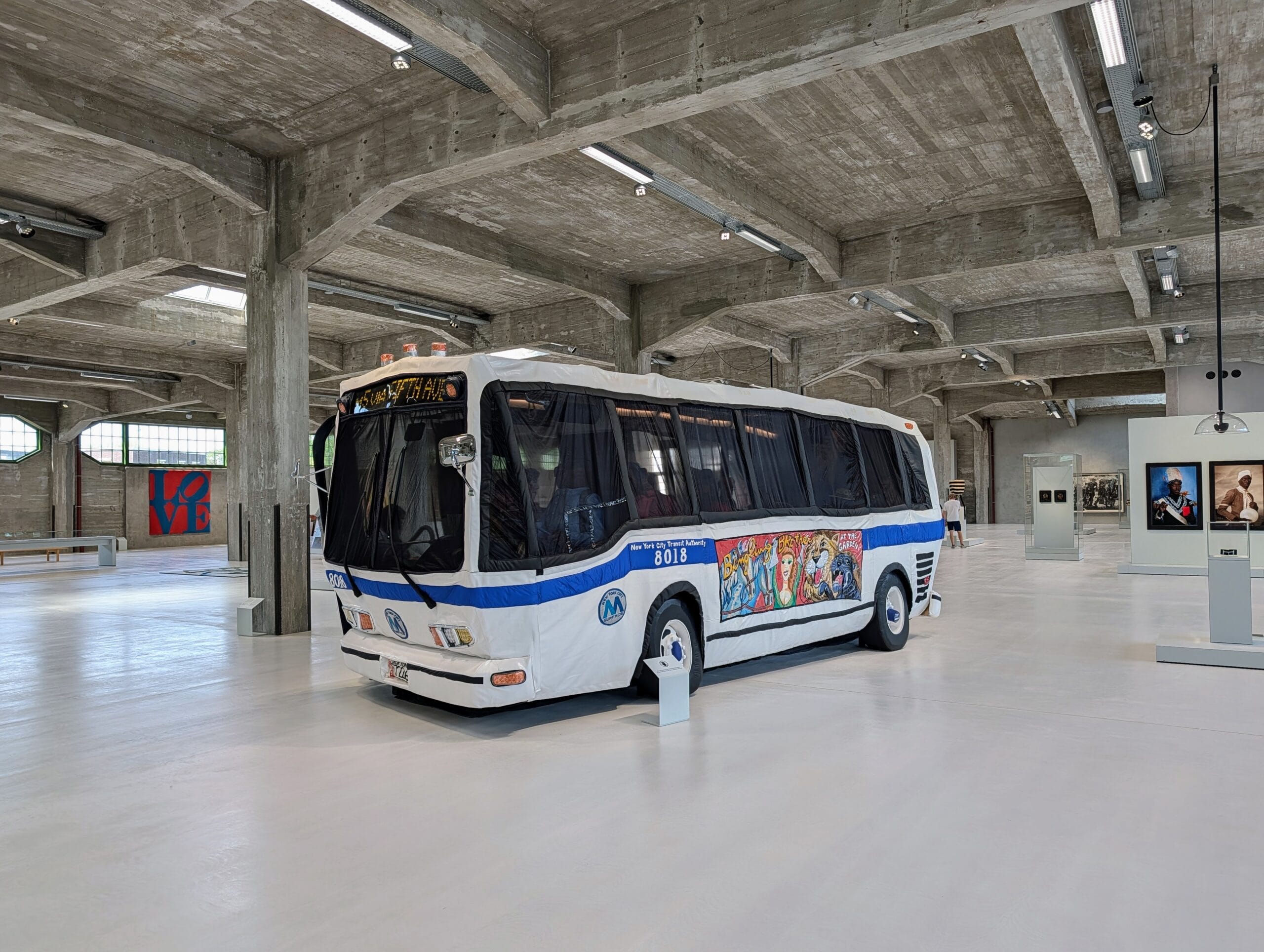 Een kunstinstallatie van een New Yorkse stadsbus bekleed met witte stof en kleurrijke illustraties in een museumzaal