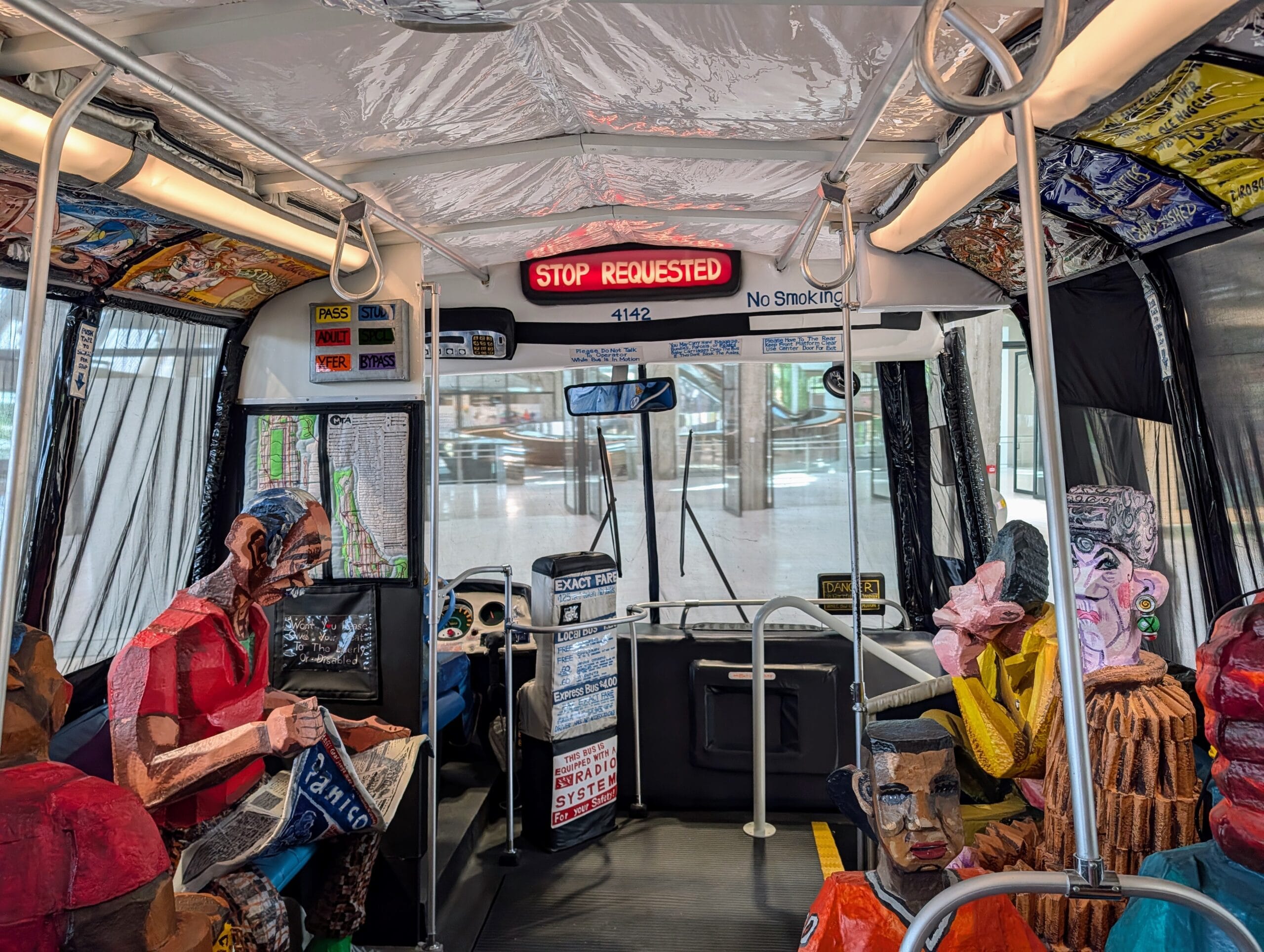 Interieur van een kunstinstallatie van een bus met kleurrijke papieren figuren als passagiers
