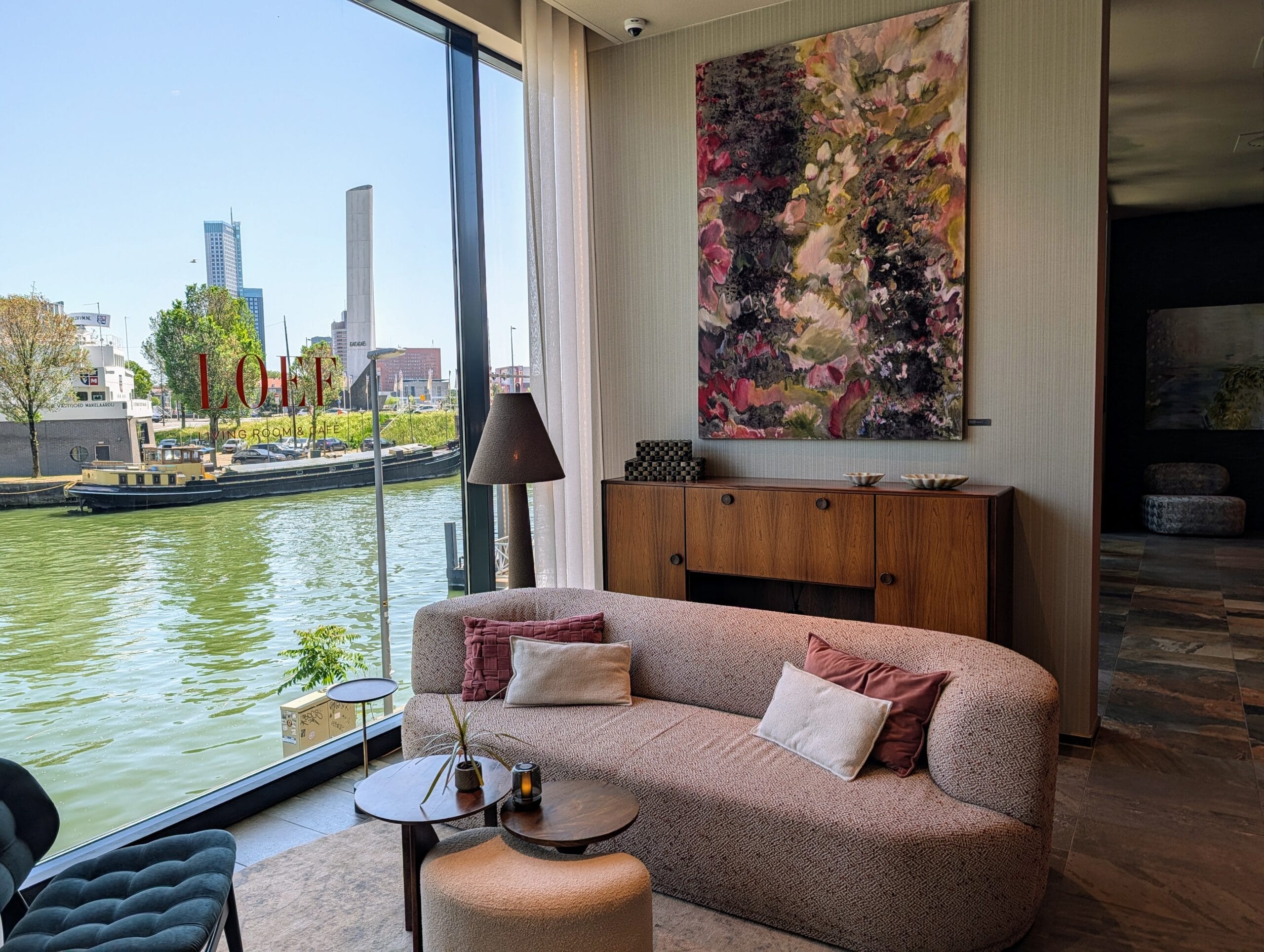 Modern interieur van Loef Living Room & Cafe met een bank bij een groot raam dat uitkijkt over het water in Rotterdam