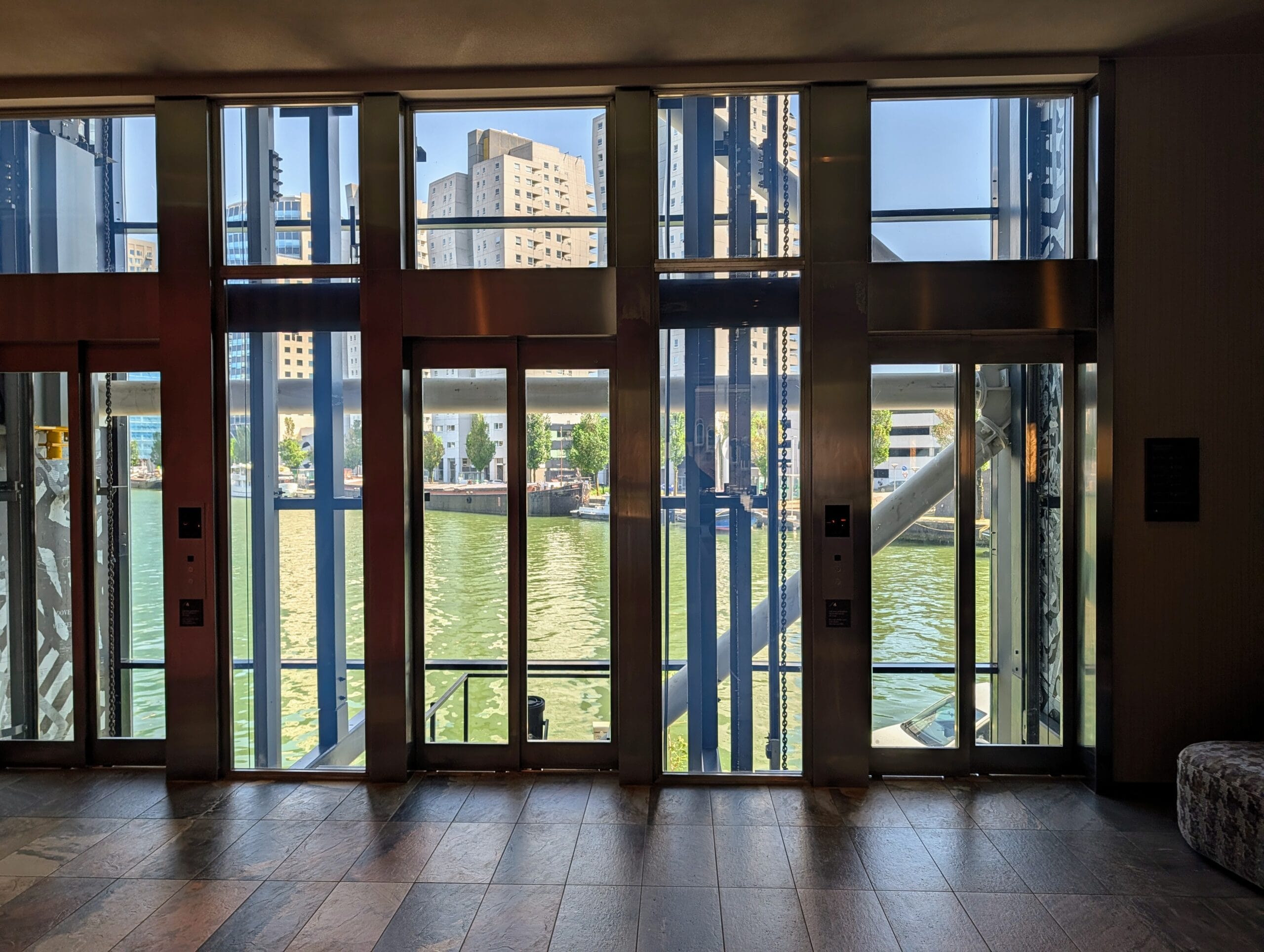 Glazen liften met uitzicht op een gracht en moderne stadsgebouwen