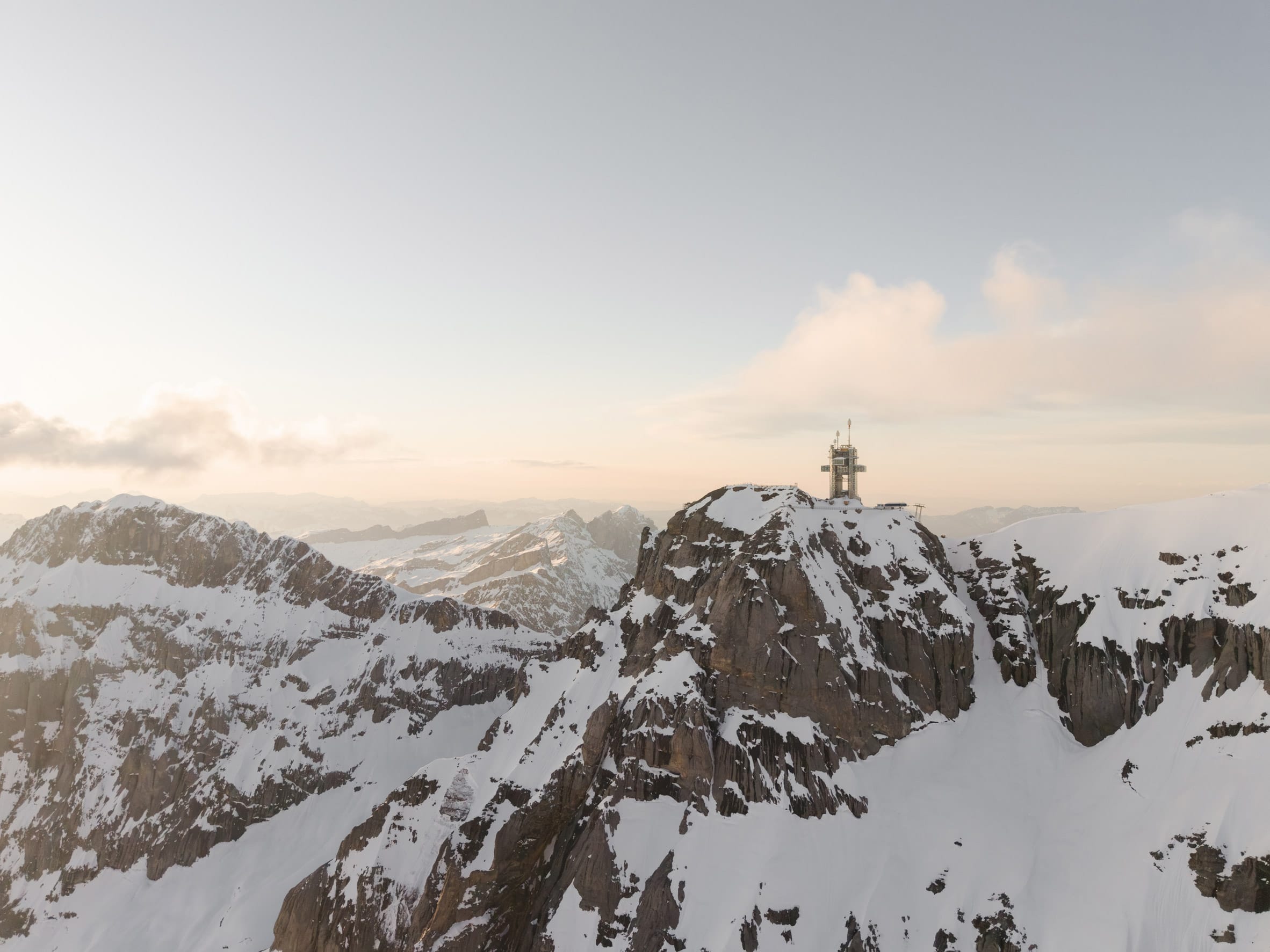Een winterse weergave van de vernieuwde Titlis Tower in Engelberg, deels bedekt met sneeuw te midden van een wit berglandschap