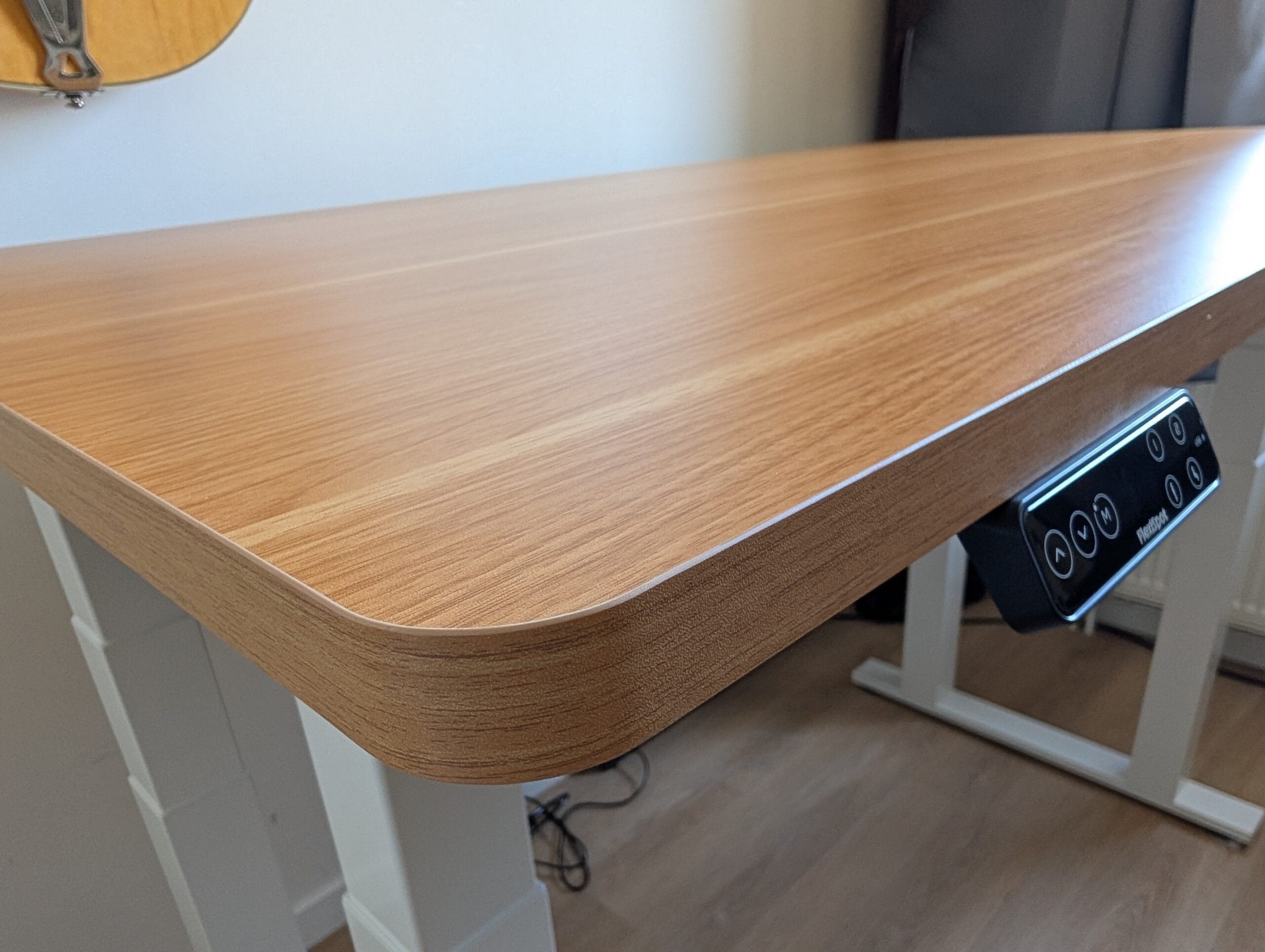 Houten bureaublad van een in hoogte verstelbaar bureau met afgeronde hoeken en een digitaal bedieningspaneel