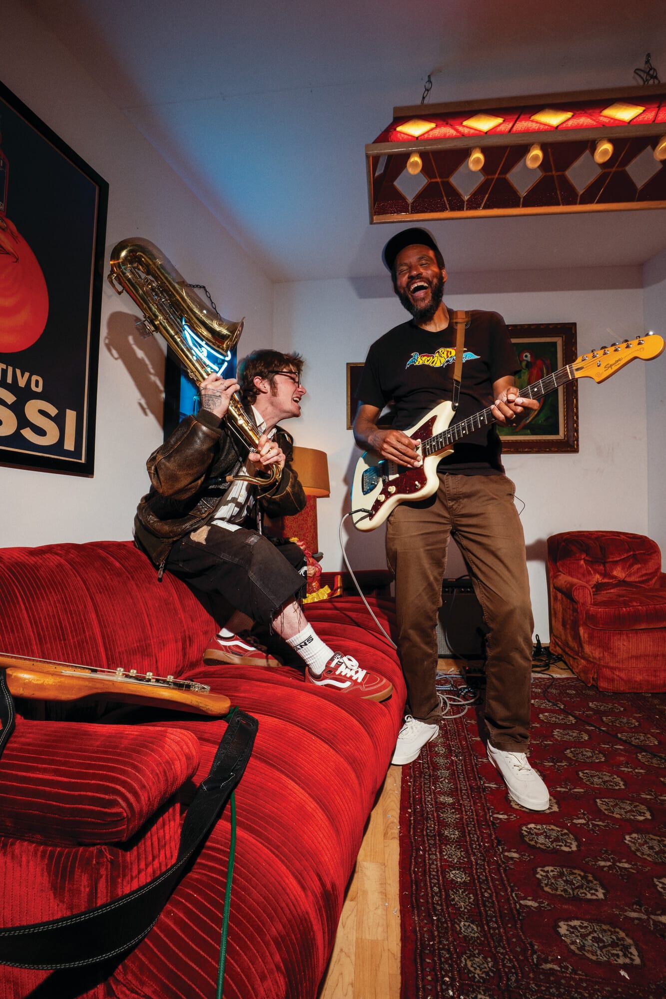 Twee muzikanten maken plezier tijdens een jamsessie in een woonkamer met een saxofoon en een elektrische gitaar