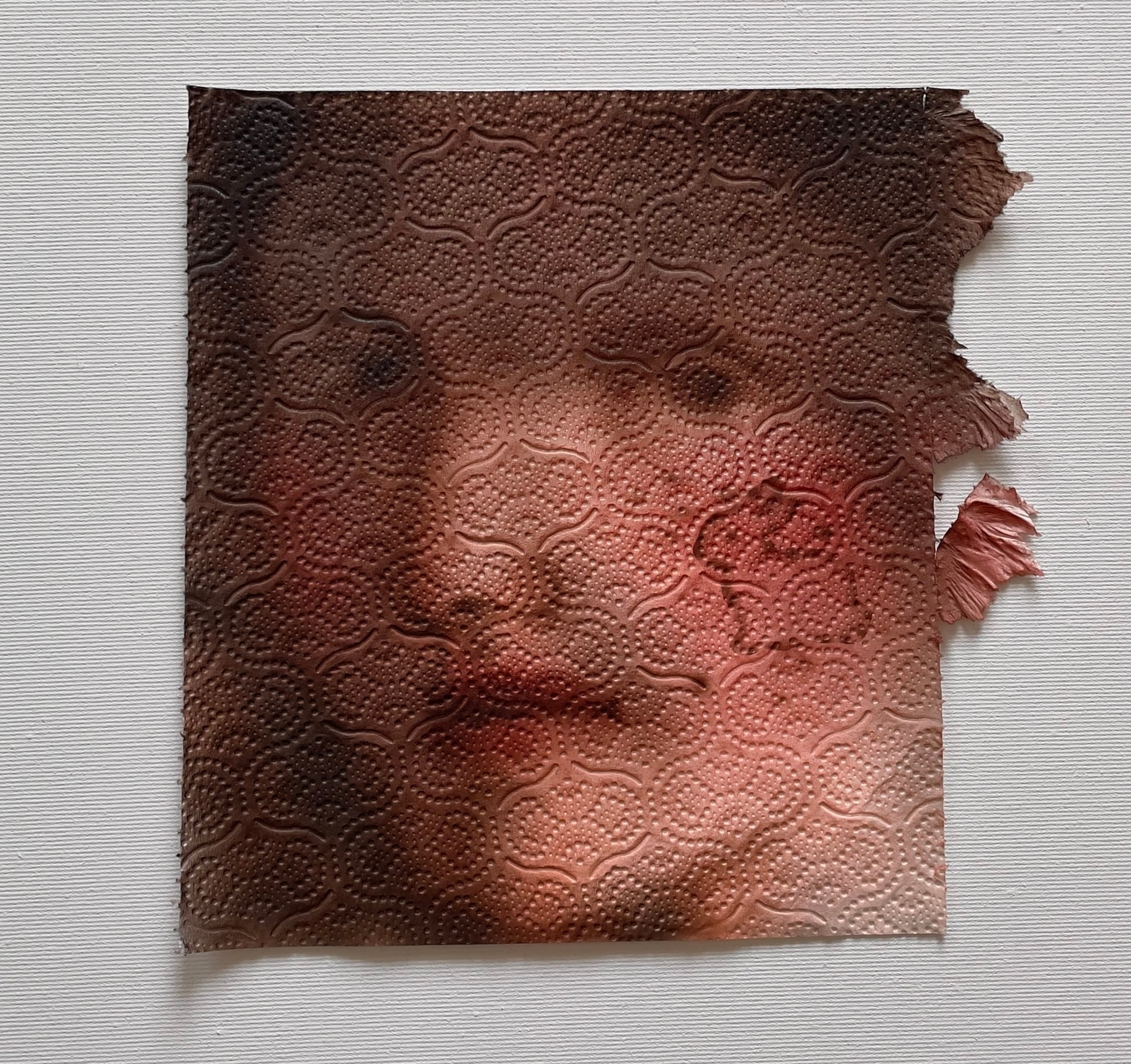 Een portret van een gezicht geschilderd op een stuk keukenpapier met een reliëfpatroon en gescheurde randen