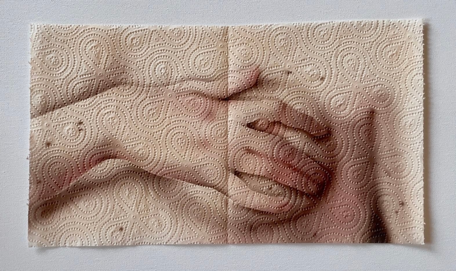 Schilderij van twee handen op keukenpapier met een reliëfpatroon van bloemen