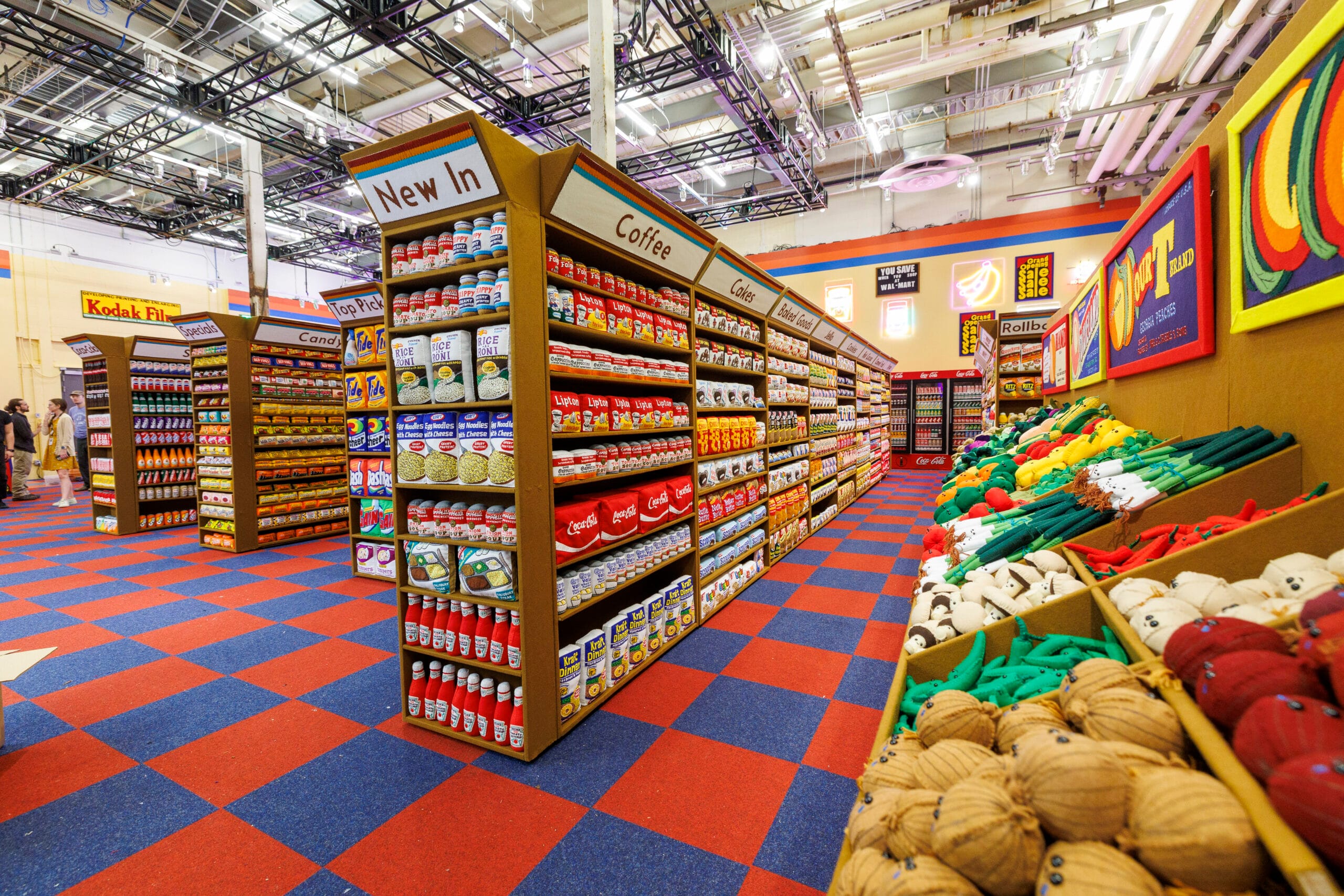 Overzicht van een kleurrijke supermarktinstallatie volledig gemaakt van vilt, met schappen vol handgemaakte producten