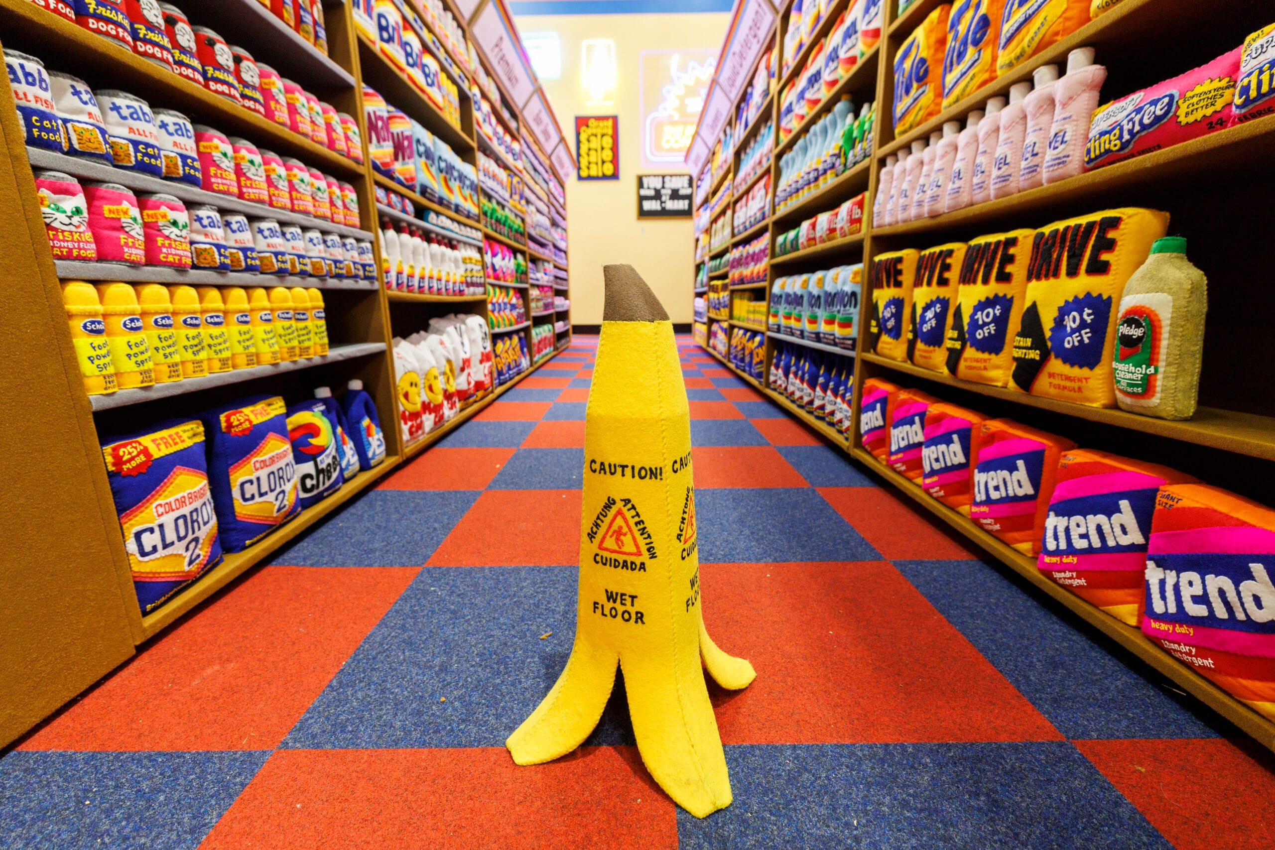 Een vilten waarschuwingskegel in de vorm van een bananenschil staat in een gangpad vol vilten huishoudproducten