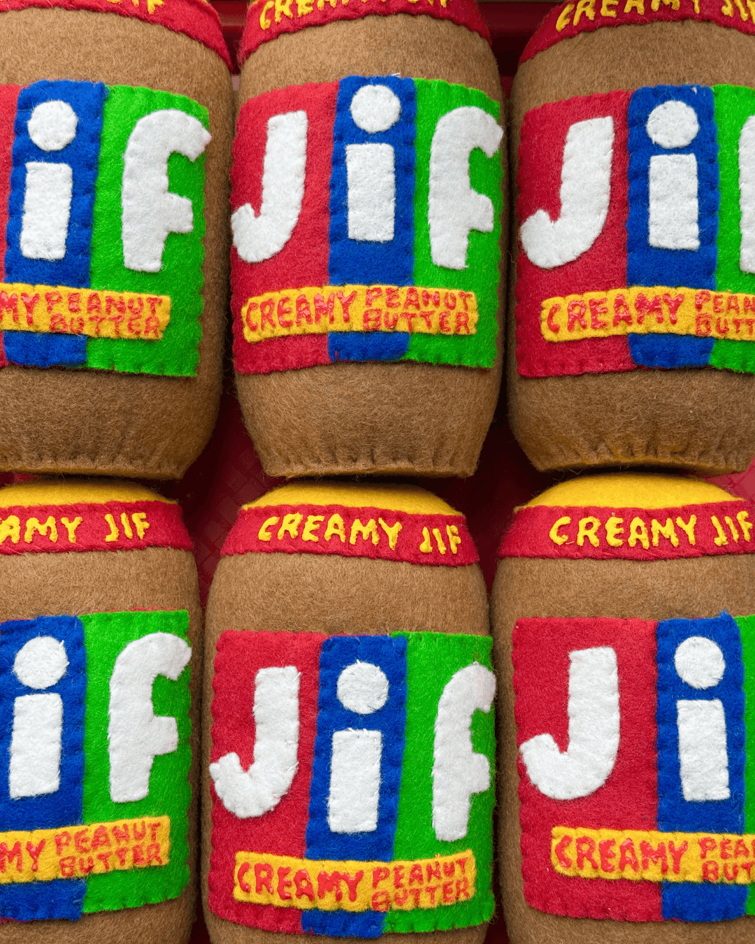 Handgemaakte vilten potten Jif Creamy Peanut Butter met kleurrijke labels in rood, blauw en groen