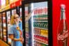 Een vrouw pakt een frisdrankblikje van vilt uit een koeling in een supermarkt die volledig uit viltkunst bestaat