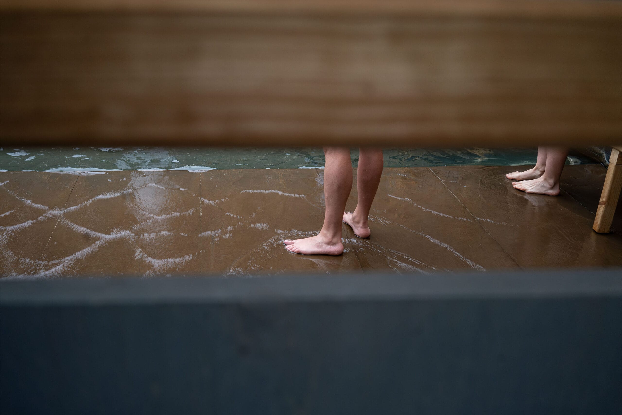 Blote voeten van bezoekers op de natte tegels van een van de Round About Baths in Logroño