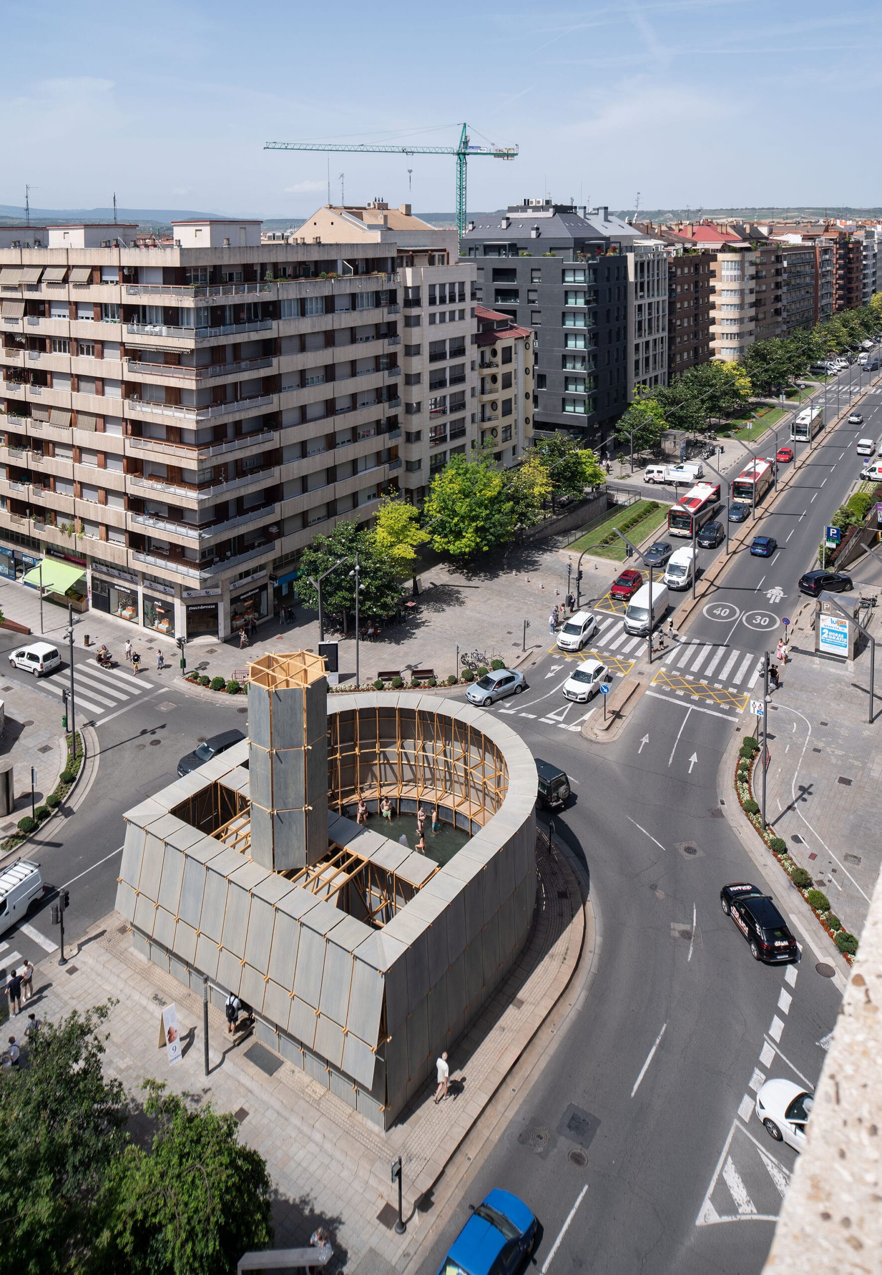 Luchtfoto van de Round About Baths: een houten constructie met een centraal bad op een rotonde midden in de stad